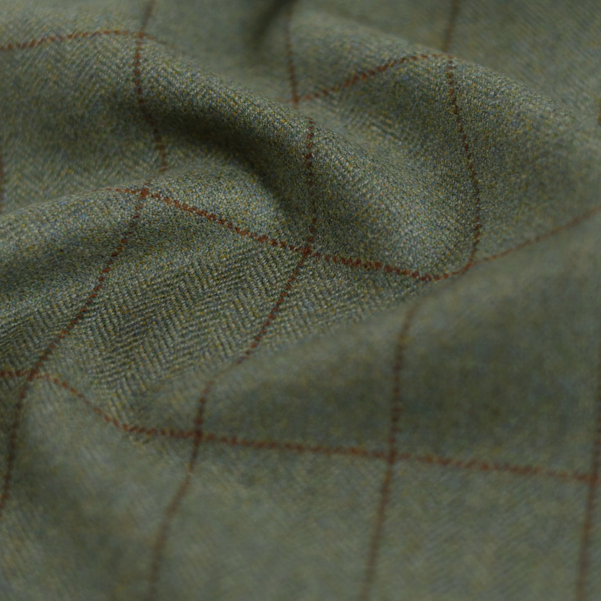 Close-up of Campbells of Beauly House Tweed 30174: greenish tweed with subtle herringbone texture, fine brown check lines, and soft folds—perfect for bespoke tailoring.