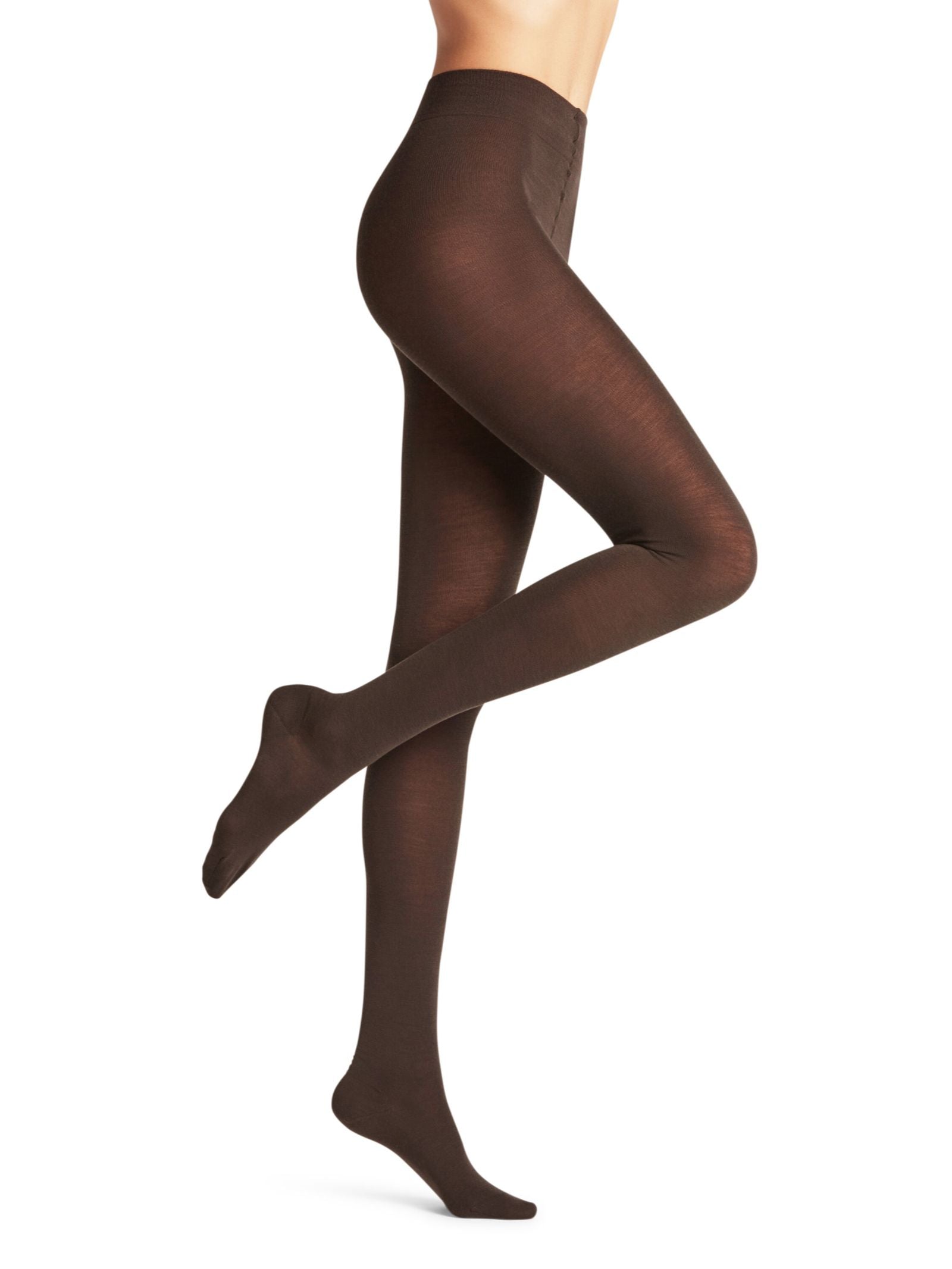 A person models FALKE Merino Tights in opaque brown, standing against a white background with one leg bent. The image focuses on the lower torso and legs, highlighting the soft merino wool texture.