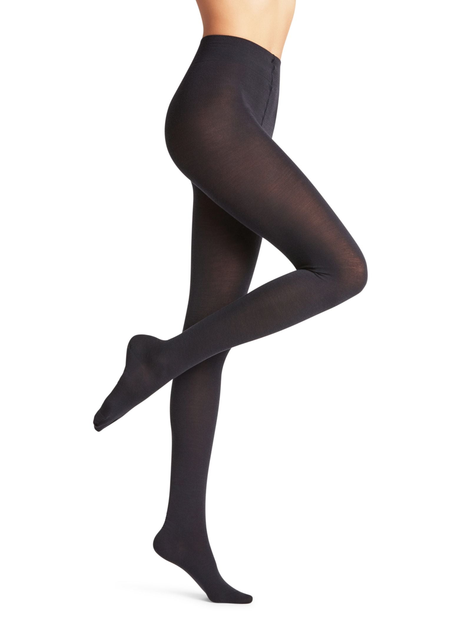 A person models FALKE Merino Tights in opaque black, standing on one leg with the other bent at the knee against a plain white background. The photo highlights the legs and lower torso.