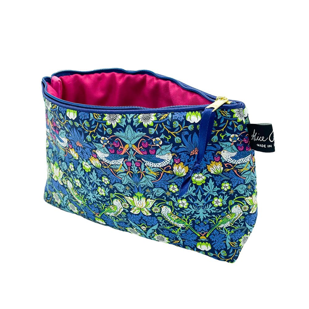The Alice Caroline Liberty Print Cosmetic Bag features zippered fabric with blue, green, and white floral and bird designs, a bright pink lining, and a small black Alice Caroline label on the side.