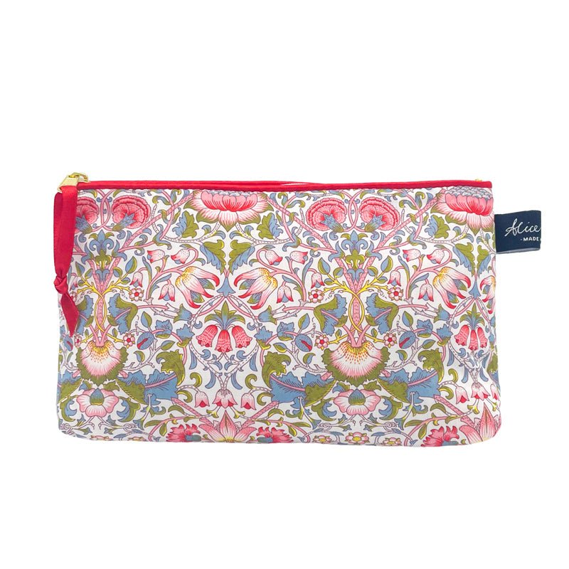 The Alice Caroline Liberty Print Cosmetic Bag features a vibrant floral and leaf pattern in pink, green, and blue, inspired by Liberty prints, with a red top zipper and a small blue tag on the right side.