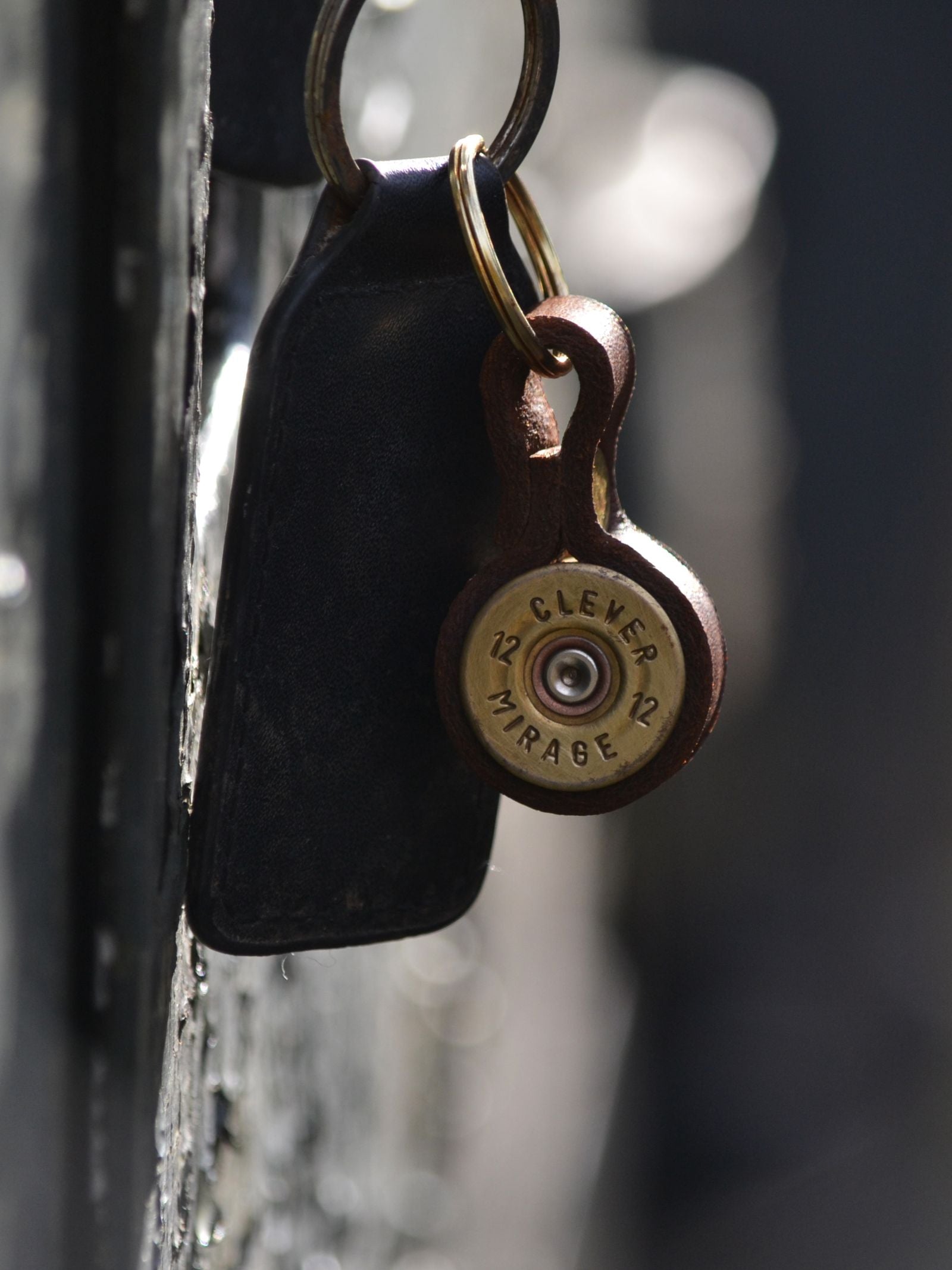 A close-up of the Cartridge Keyring by Campbell's of Beauly, featuring a black leather tag and a round brass charm crafted from a Clever Mirage shotgun shell casing—an ideal country sport gift.