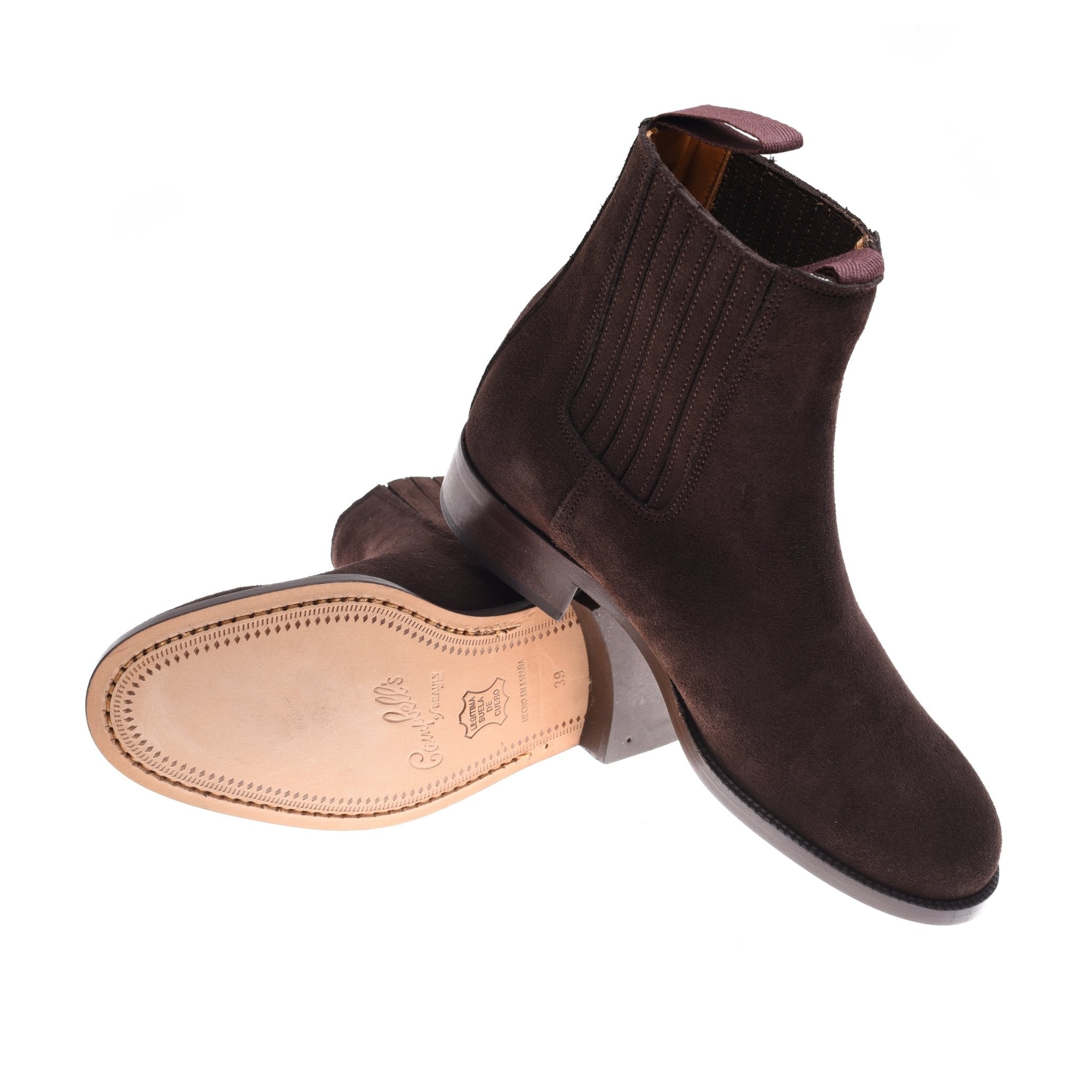A pair of Campbells of Beauly Suede Chelsea Ankle Boots—one upright, one on its side to display the light tan leather Commando sole with embossed branding—expertly crafted in Northamptonshire.