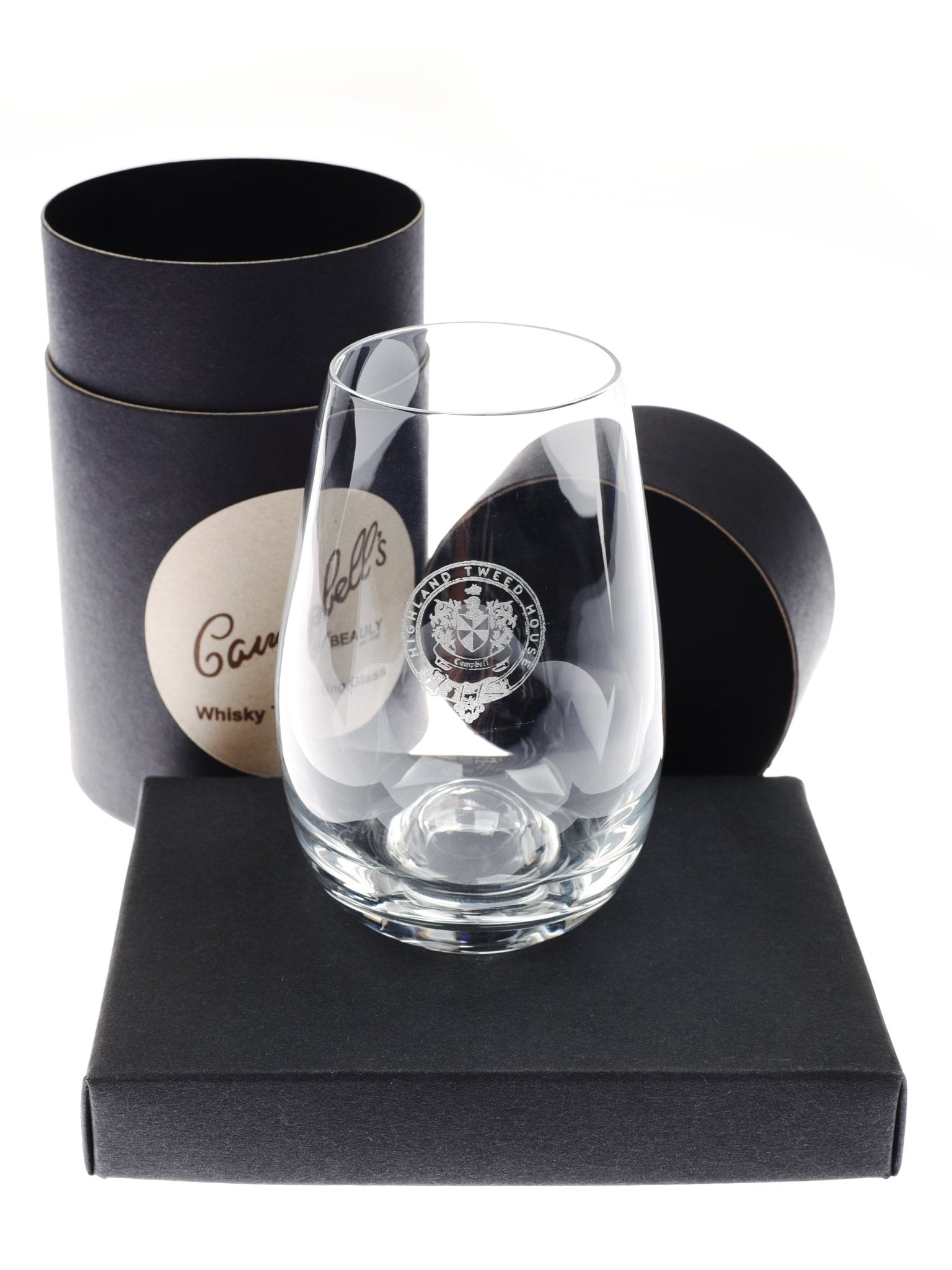 A clear, tulip-shaped Whisky Tasting Glass by Campbell's of Beauly rests on a black box, with a cylindrical black case featuring the Campbell's of Beauly logo standing behind it—an ideal gift for whisky lovers. The case’s lid is slightly open.