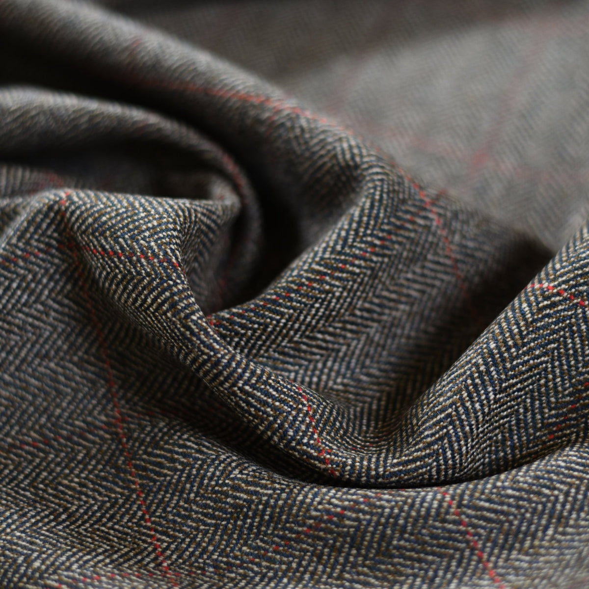 Close-up of Campbells of Beauly House Tweed 68866: lightweight herringbone fabric in gray with fine red lines, soft folds, and texture—showcasing timeless craftsmanship.