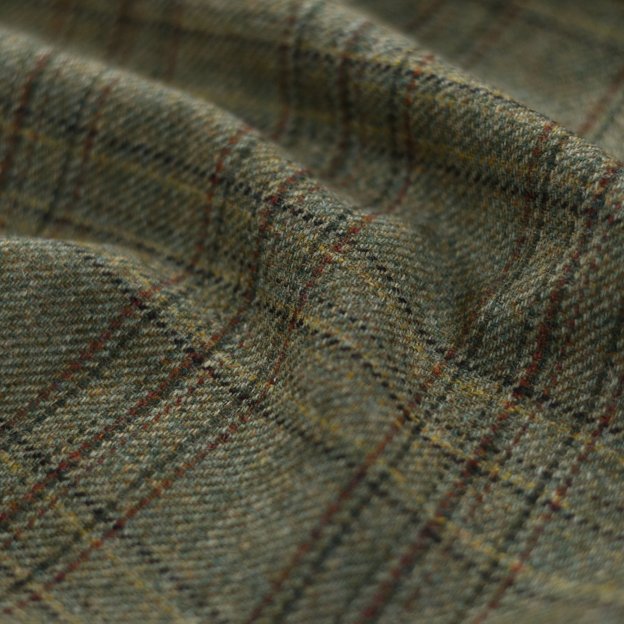Close-up of House Tweed 81766 by Campbells of Beauly, featuring green and brown plaid with intersecting red and yellow lines. The textured wool fabric highlights a classic checkered design and traditional craftsmanship.