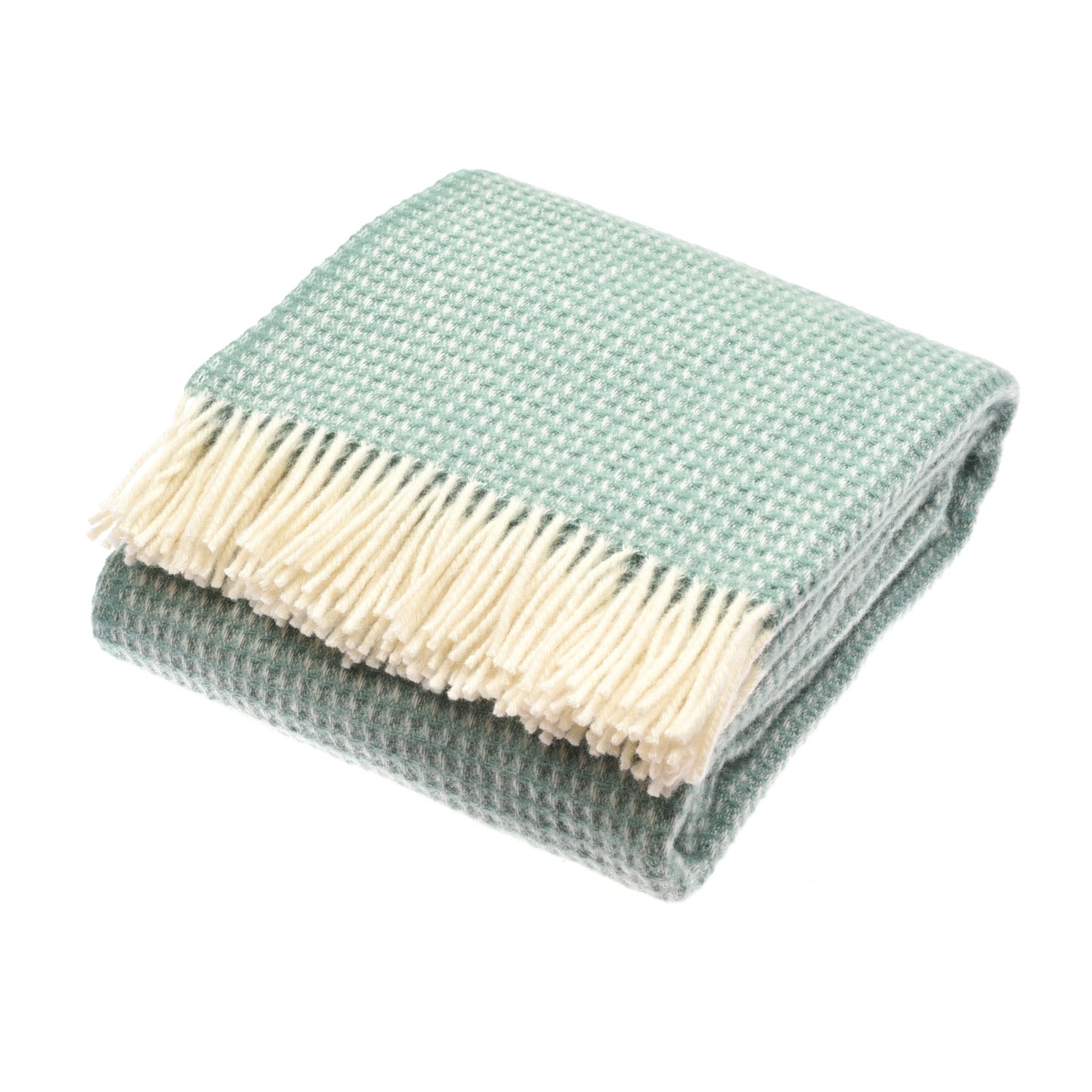 The Campbells of Beauly Honeycomb Lambswool Throw in Glacier is shown folded on a white background, featuring a houndstooth pattern and cream-colored fringes.
