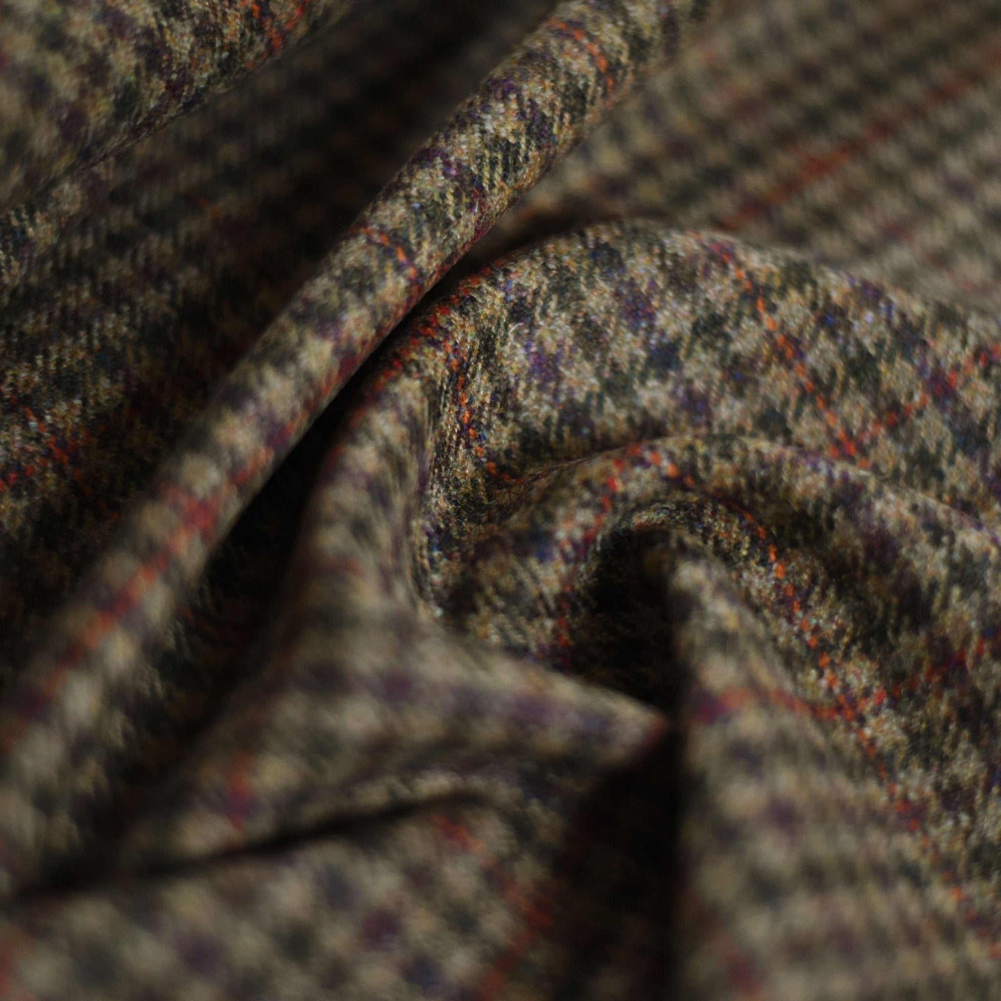 A close-up of Campbells of Beauly House Tweed 84958: brown and gray plaid wool with subtle red and blue lines, softly draped to highlight its rich texture and traditional Scottish craftsmanship.