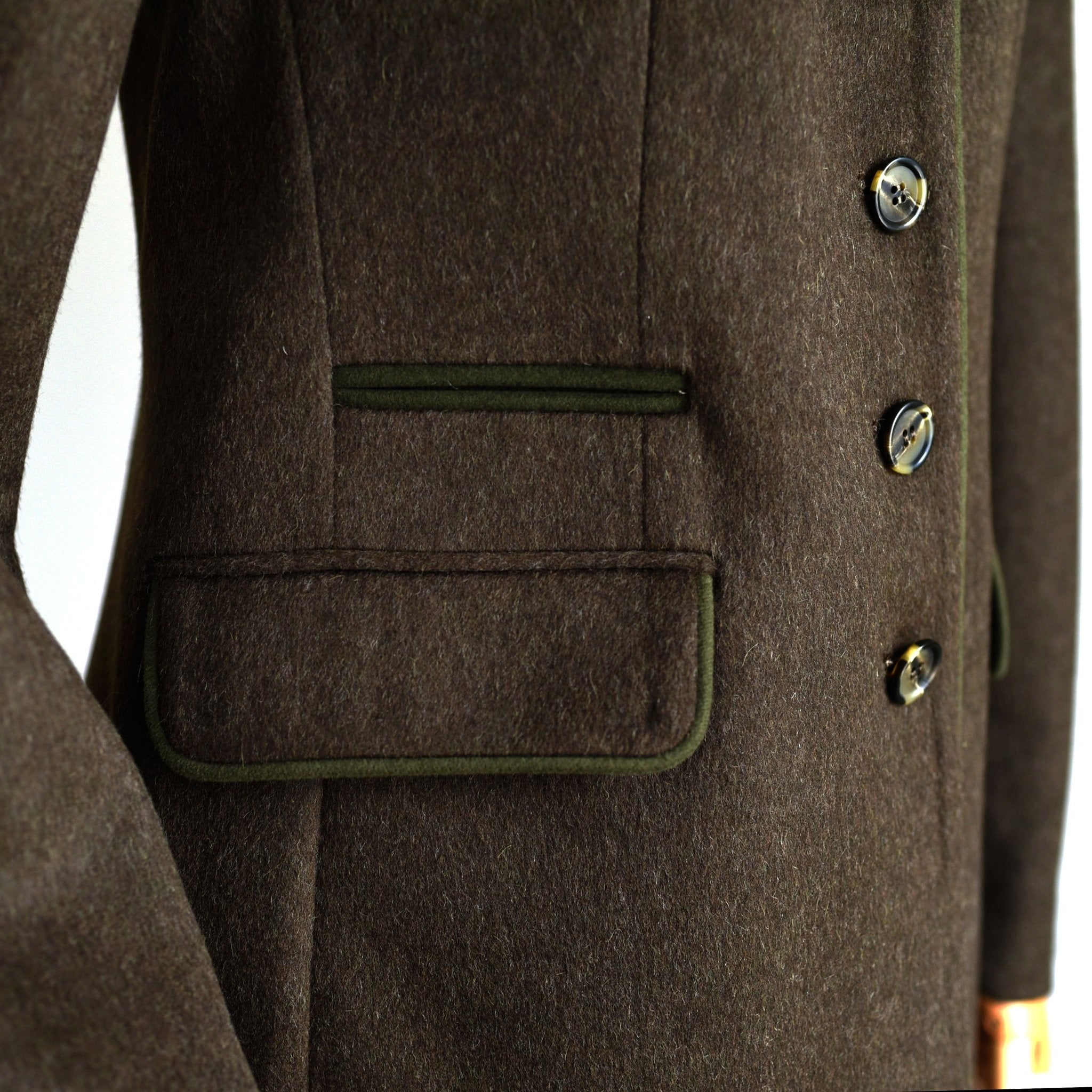 Close-up of the Campbells of Beauly Loden Green Millie Coat, featuring Austrian loden wool, three buttons, and two front pockets with dark green trim. Image highlights the midsection and side of this Nehru style wool blazer.