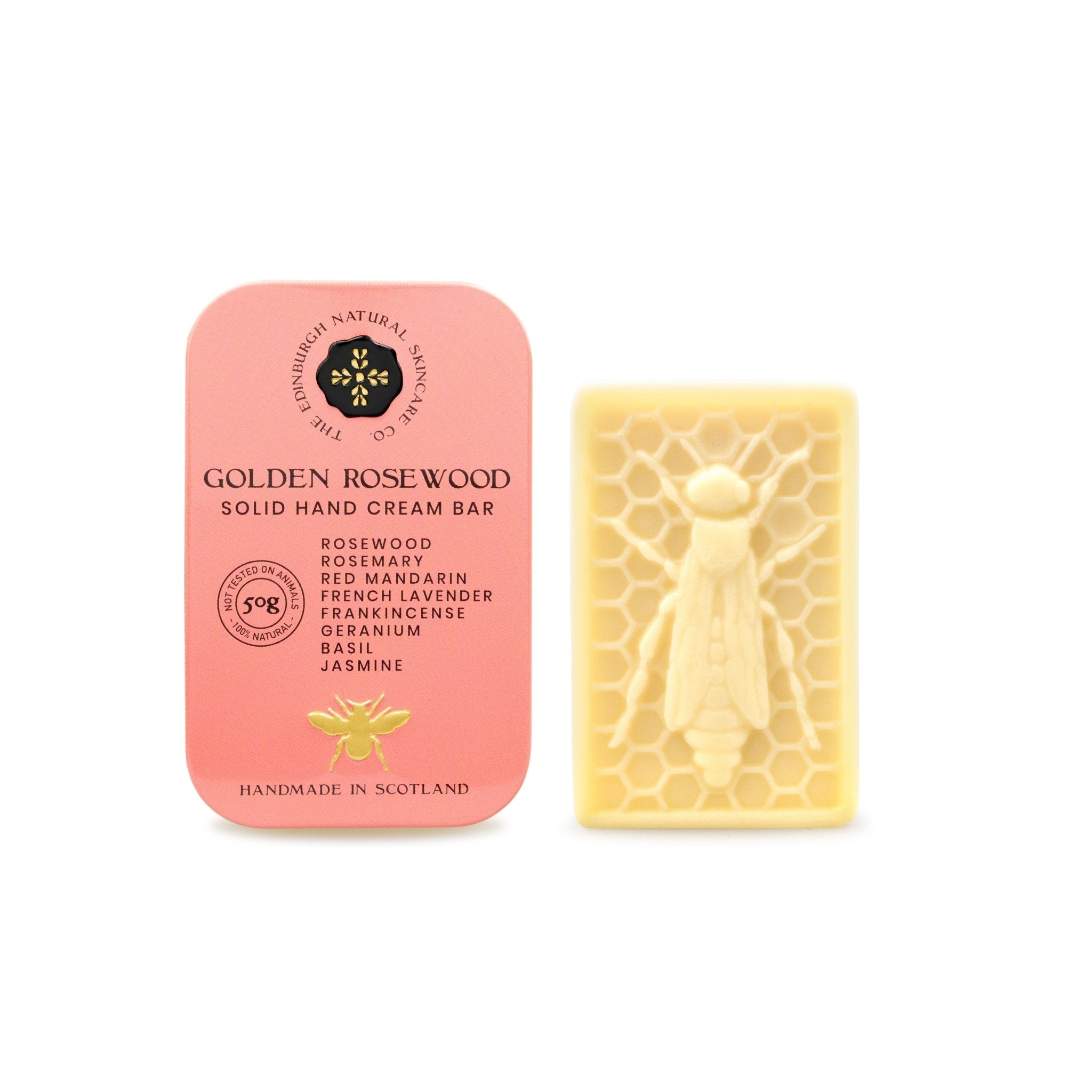 A pink tin of The Edinburgh Natural Skincare Companys Golden Rosewood Luxury Hand Cream Bar, handmade in Scotland with sustainably sourced ingredients and moisturising oils, stands beside a cream bar with a honeycomb and bee design.