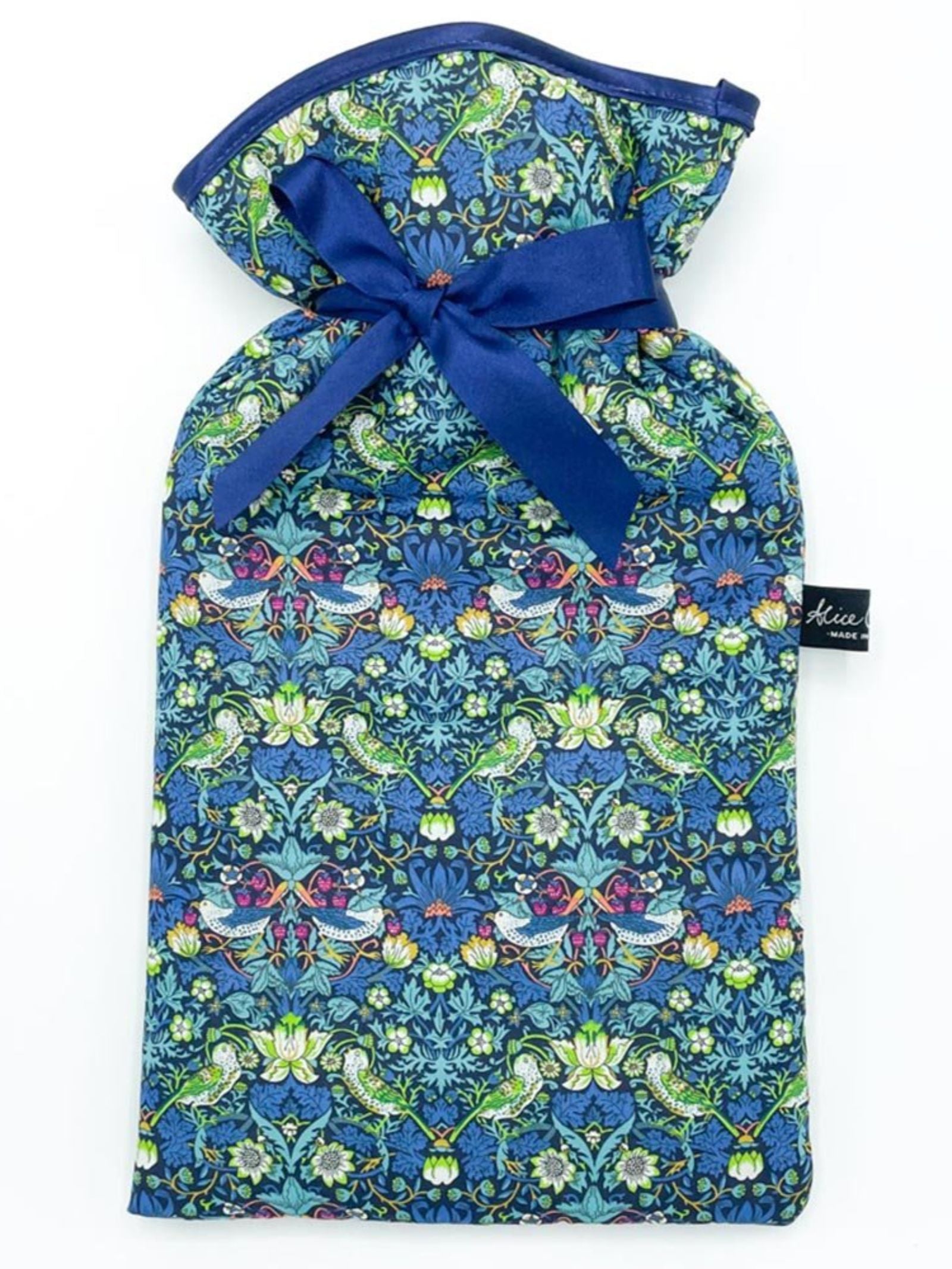 The Alice Caroline Liberty Print Hot Water Bottle features soft Liberty cotton with a blue ribbon and vibrant floral and bird patterns in blue, green, and pink, plus a small black tag with white lettering on the side.