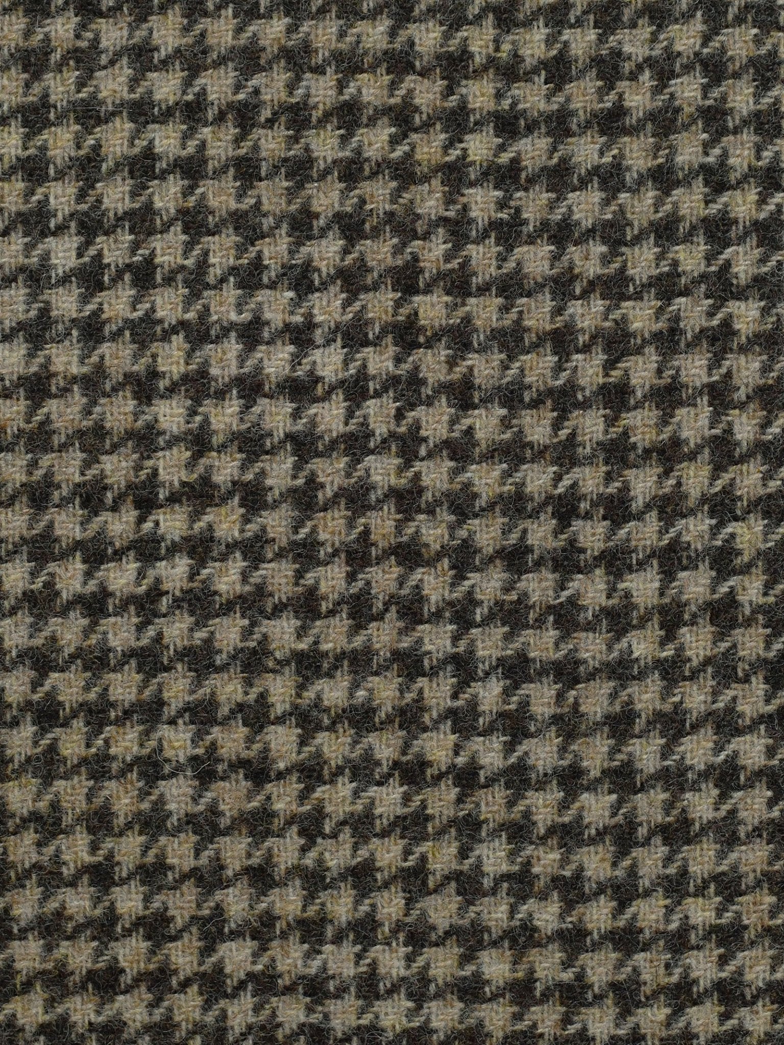 A close-up of Campbell's of Beauly House Tweed 83654 fabric, featuring a classic black and beige houndstooth pattern in 100% wool—ideal for jacketing weight garments.