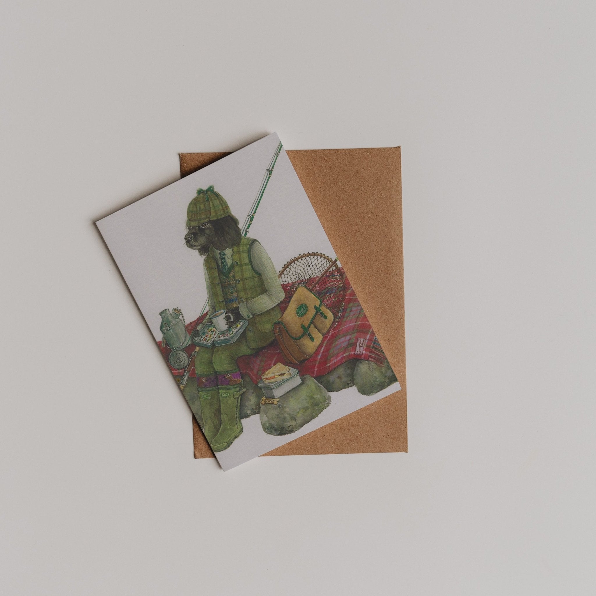 The Fisherman Greeting Card by Campbell's of Beauly features a fishing-themed character sitting on rocks with a rod, atop a brown envelope—perfect as a thank you note, shown on a plain white background.