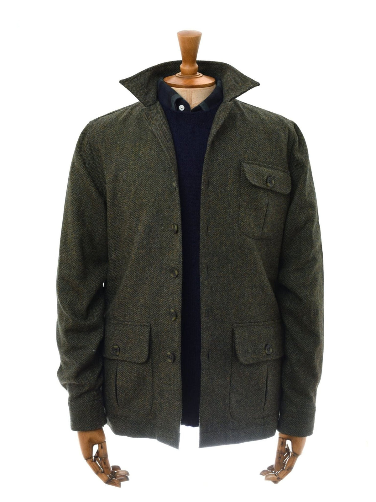 A mannequin wears the Casual Shacket by Campbell’s of Beauly—dark green Shetland tweed with a pointed collar, button front, and three pockets—layered over a navy sweater and white-collared shirt for classic style.