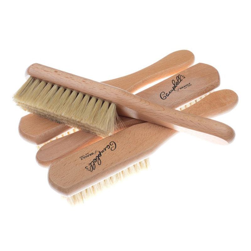Four Campbell's Clothes Brushes by Campbell's of Beauly, featuring light bristles and black-printed handles, are stacked together. Their varying bristle angles effectively remove pet hair, making them ideal for garment care.
