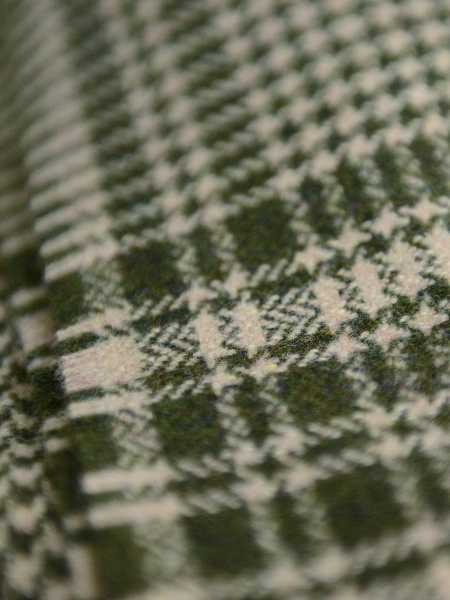 Close-up of the Crofters Blanket by Campbell's of Beauly, featuring soft green and white plaid fabric with intersecting lines and squares. The woven threads highlight its intricate design and cozy, country-inspired aesthetic.