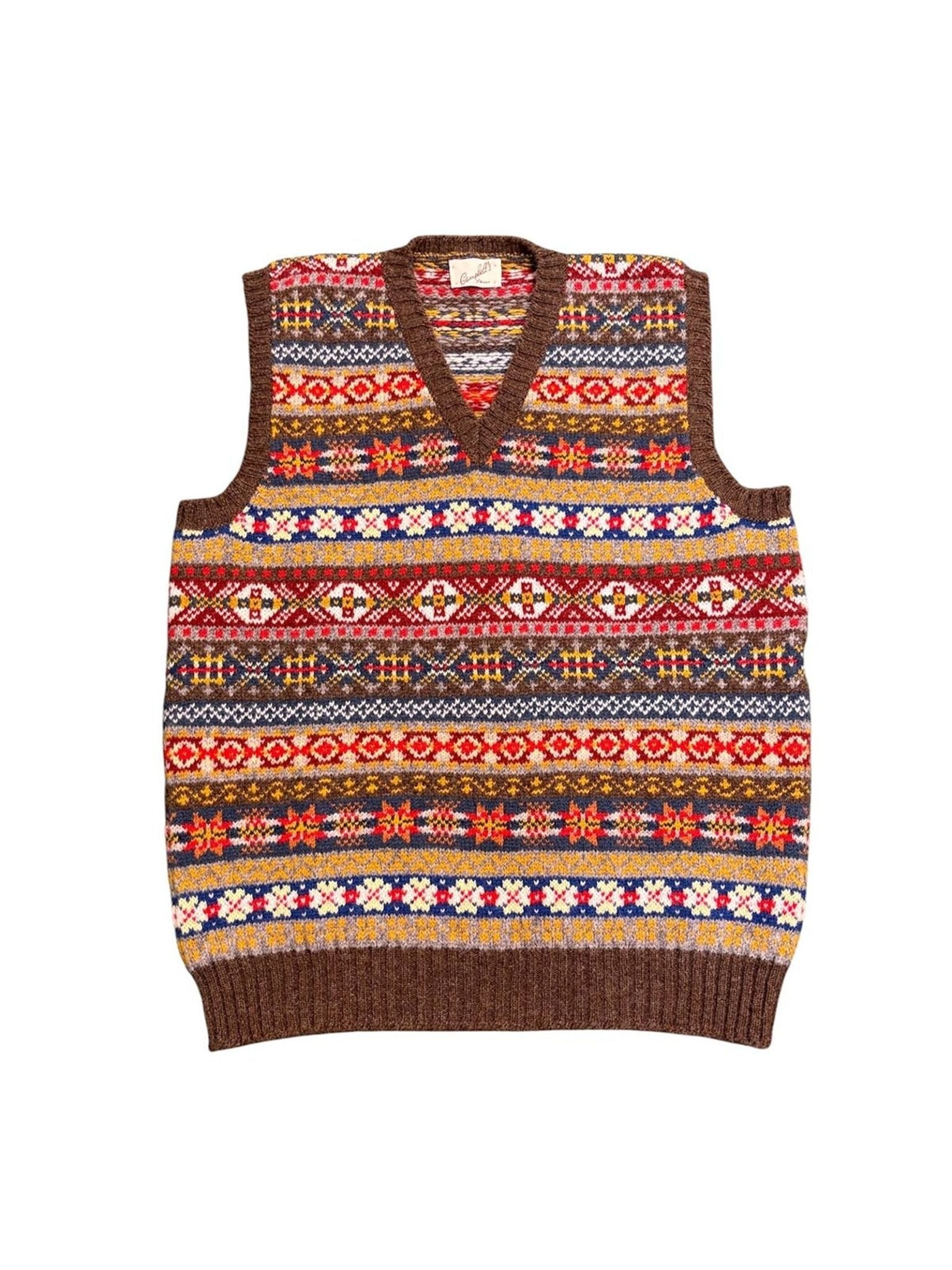 The Campbell’s of Beauly Fairisle Slipover is a knitted, sleeveless sweater vest with a V-neck, showcasing vibrant and intricate Fair Isle patterns in red, yellow, blue, and brown on a white background. Made from soft Shetland wool for warmth and comfort, it’s ideal as a stylish sleeveless layer.