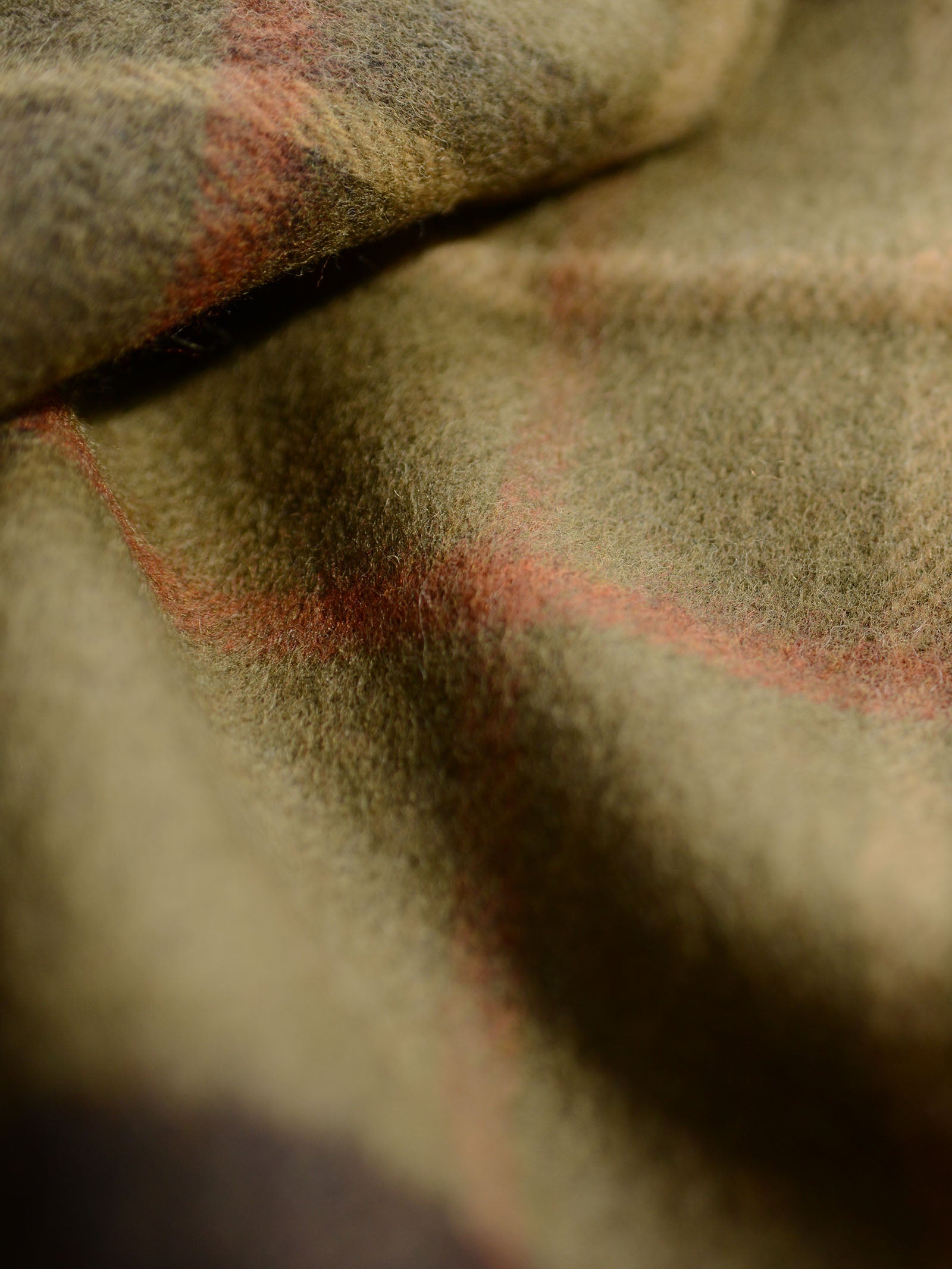 Close-up of the Glassburn Merino Throw by Campbell's of Beauly, featuring soft lambswool in muted olive green with a red plaid pattern, woven in the UK, showcasing its cosy texture and gentle folds.