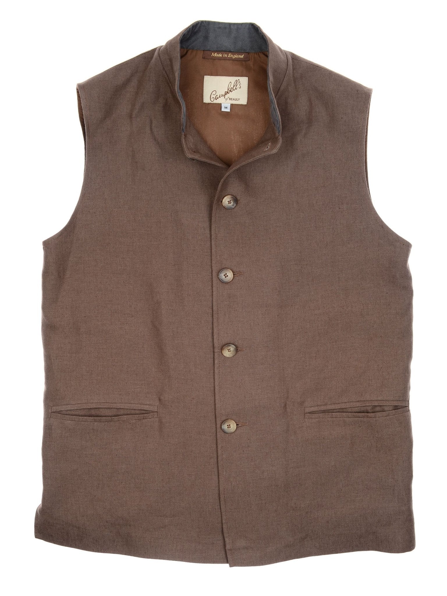 The Campbell’s of Beauly Linen Nehru Gilet is a sleeveless brown vest with a stand collar, two front pockets, and an inner neck label. Laid flat on a white background, it’s an elegant choice for summer layering.