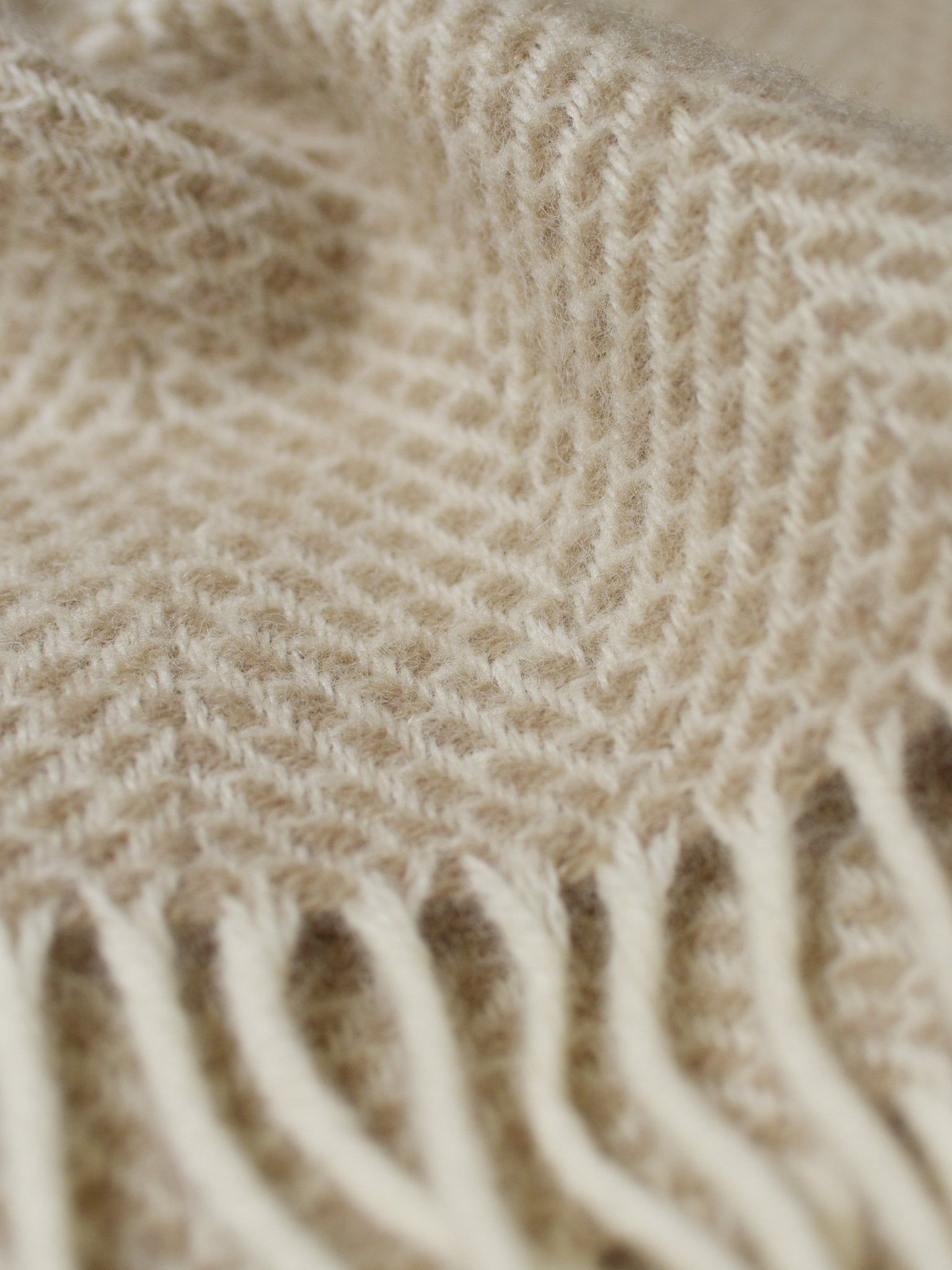 Close-up of the Stipled Twill Blanket by Campbell's of Beauly in beige, featuring a herringbone pattern, fringed ends, and highlighting its breathable weave and detailed texture.