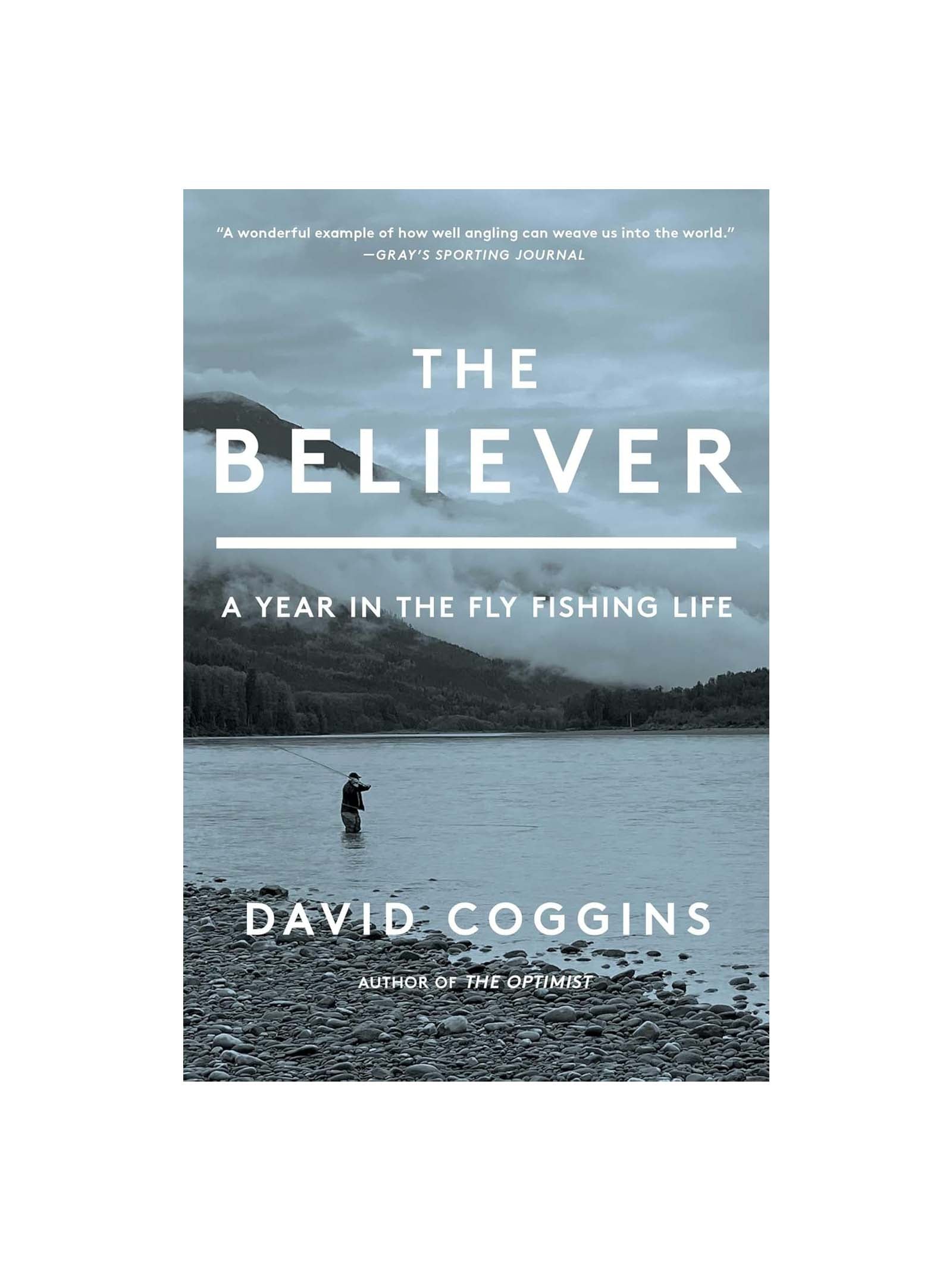 The cover of The Believer: A Year in the Fly Fishing Life by David Coggins features an angler fishing in a calm lake, set against misty mountains and forests under a cloudy sky, reflecting the tranquility of fly fishing.