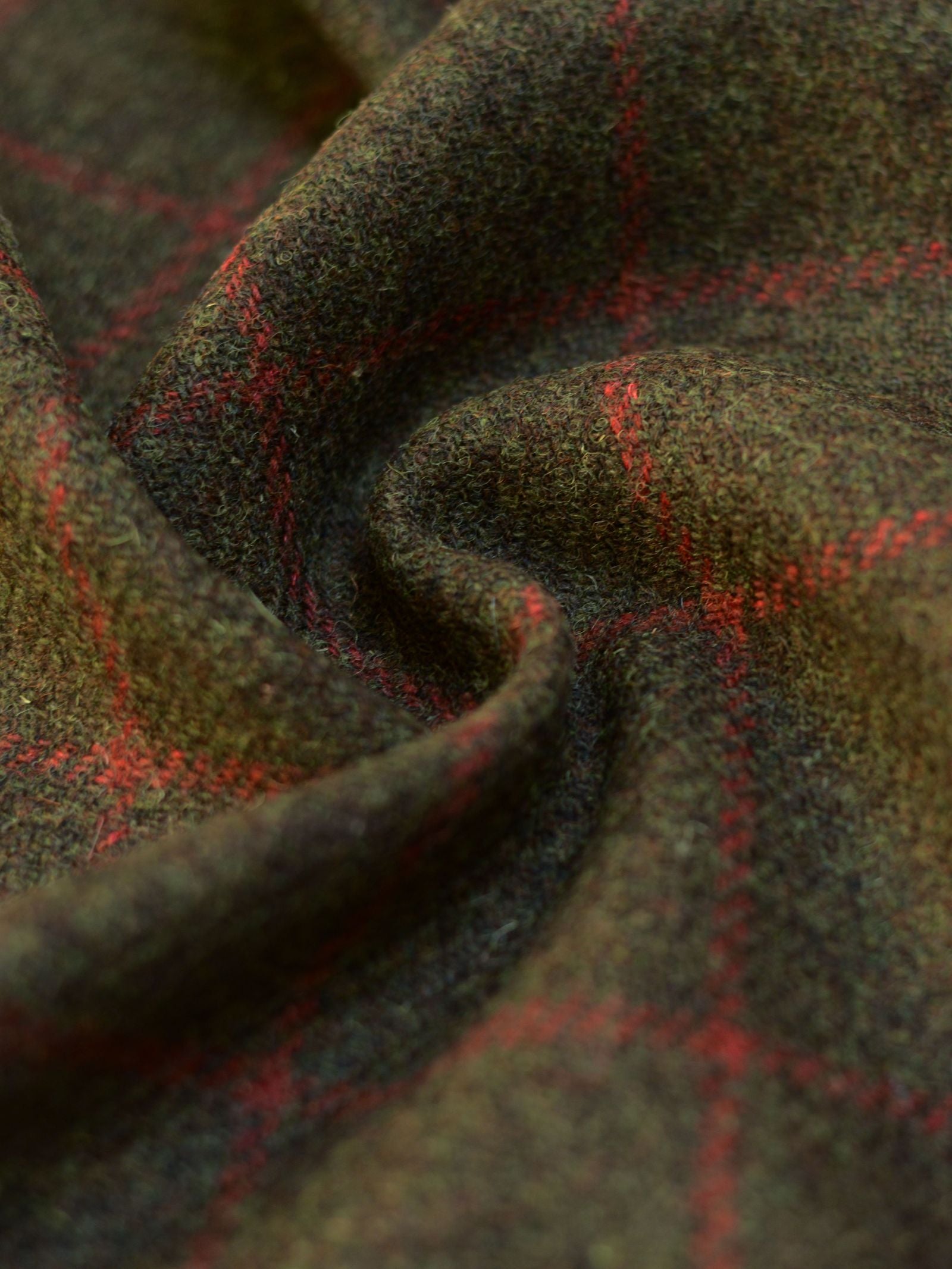 A close-up of Harris Tweed 93907 by Campbell's of Beauly shows lightweight brown and green tweed with red windowpane plaid, featuring a soft textured surface and gentle folds—reflecting Scottish weaving heritage.