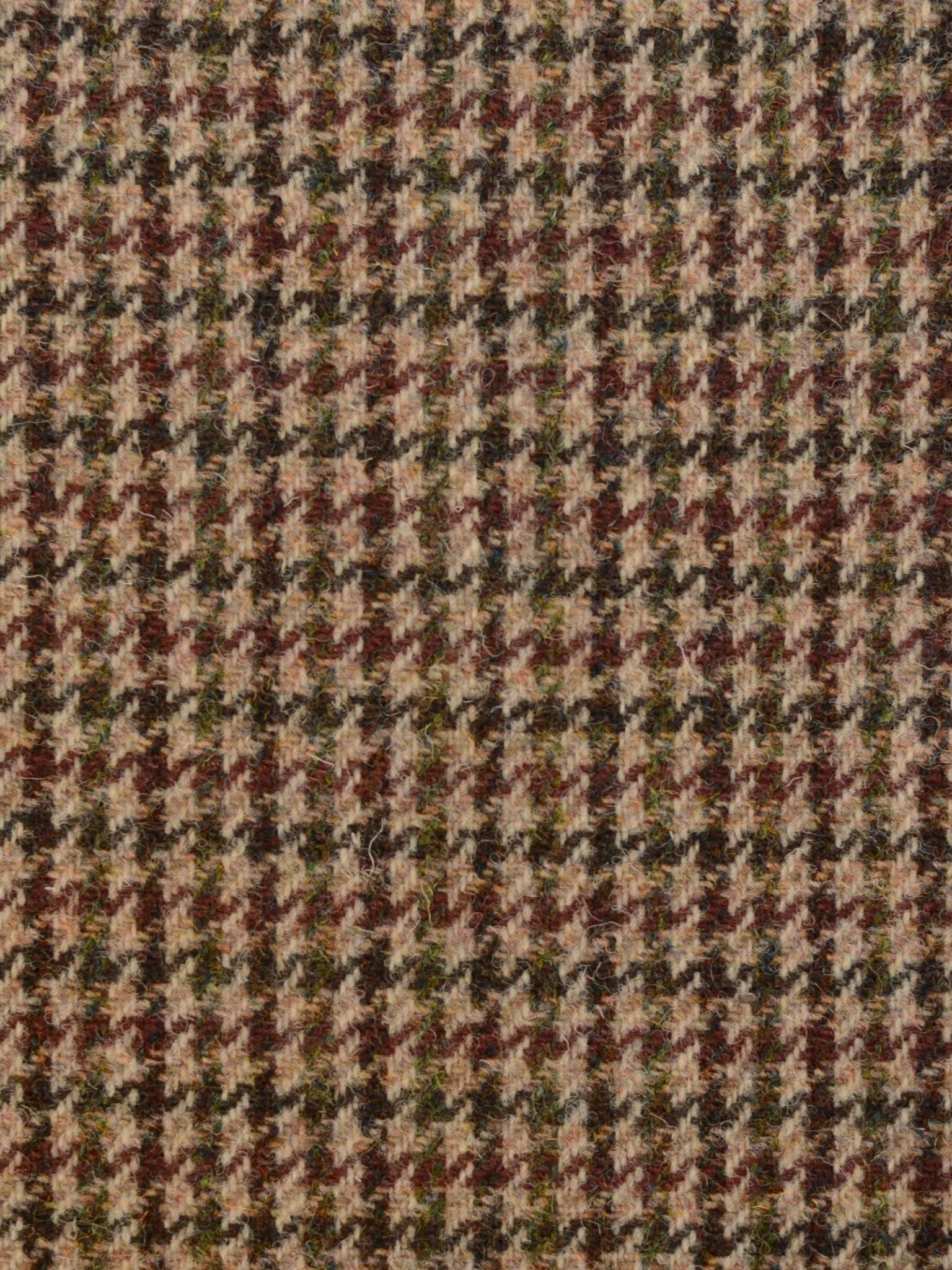 Close-up of Campbell's of Beauly Harris Tweed 93904: a featherweight houndstooth-patterned fabric in brown, beige, black, and green tones with a textured woven finish.