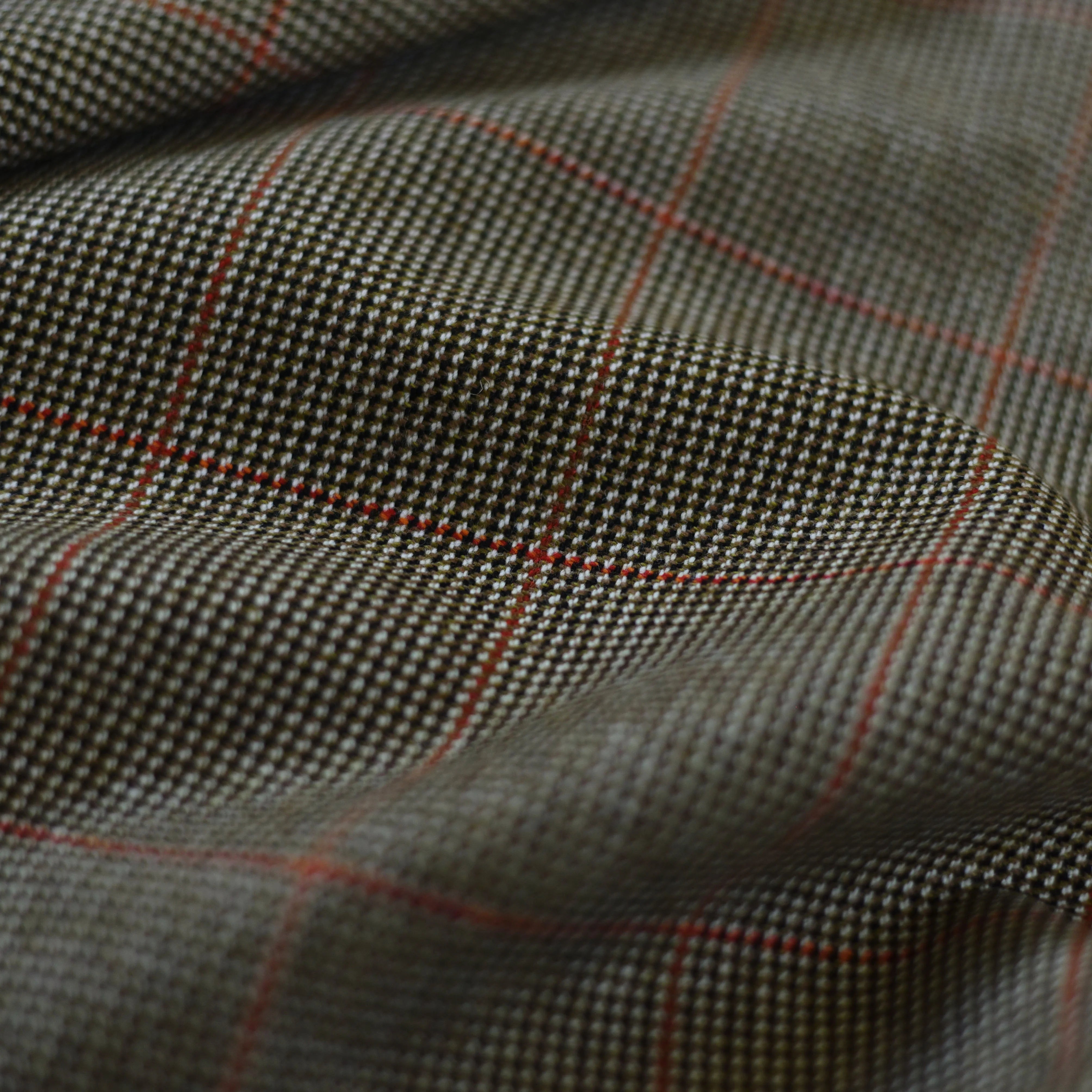 A close-up of Campbell's of Beauly House Tweed 30242: traditional tweed fabric with a black and white houndstooth pattern, subtle red grid, and gentle folds—perfect for those seeking tweed by the metre.