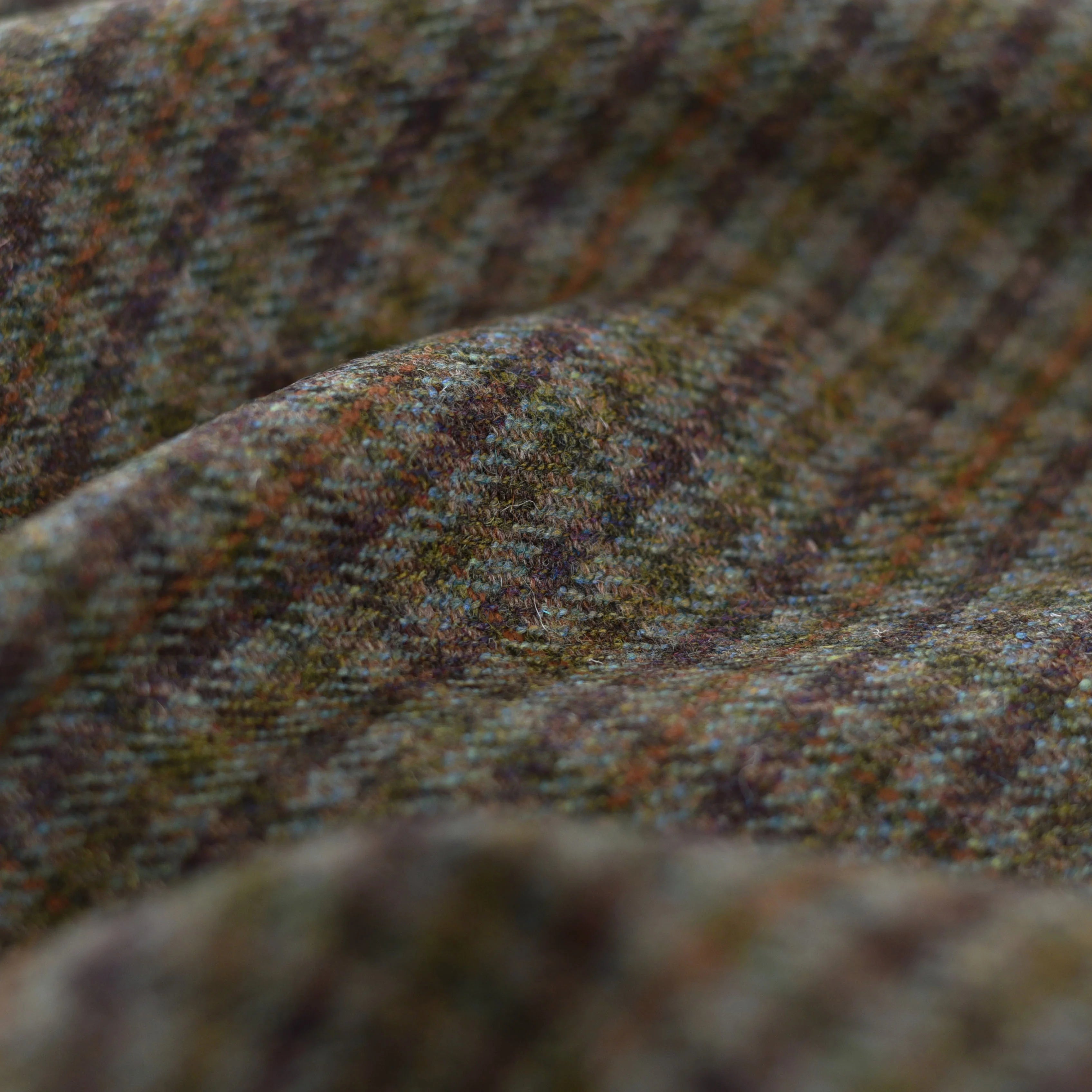 Close-up of House Tweed 30246 by Campbell's of Beauly, featuring brown, green, and orange houndstooth with textured folds—ideal for tailored garments.