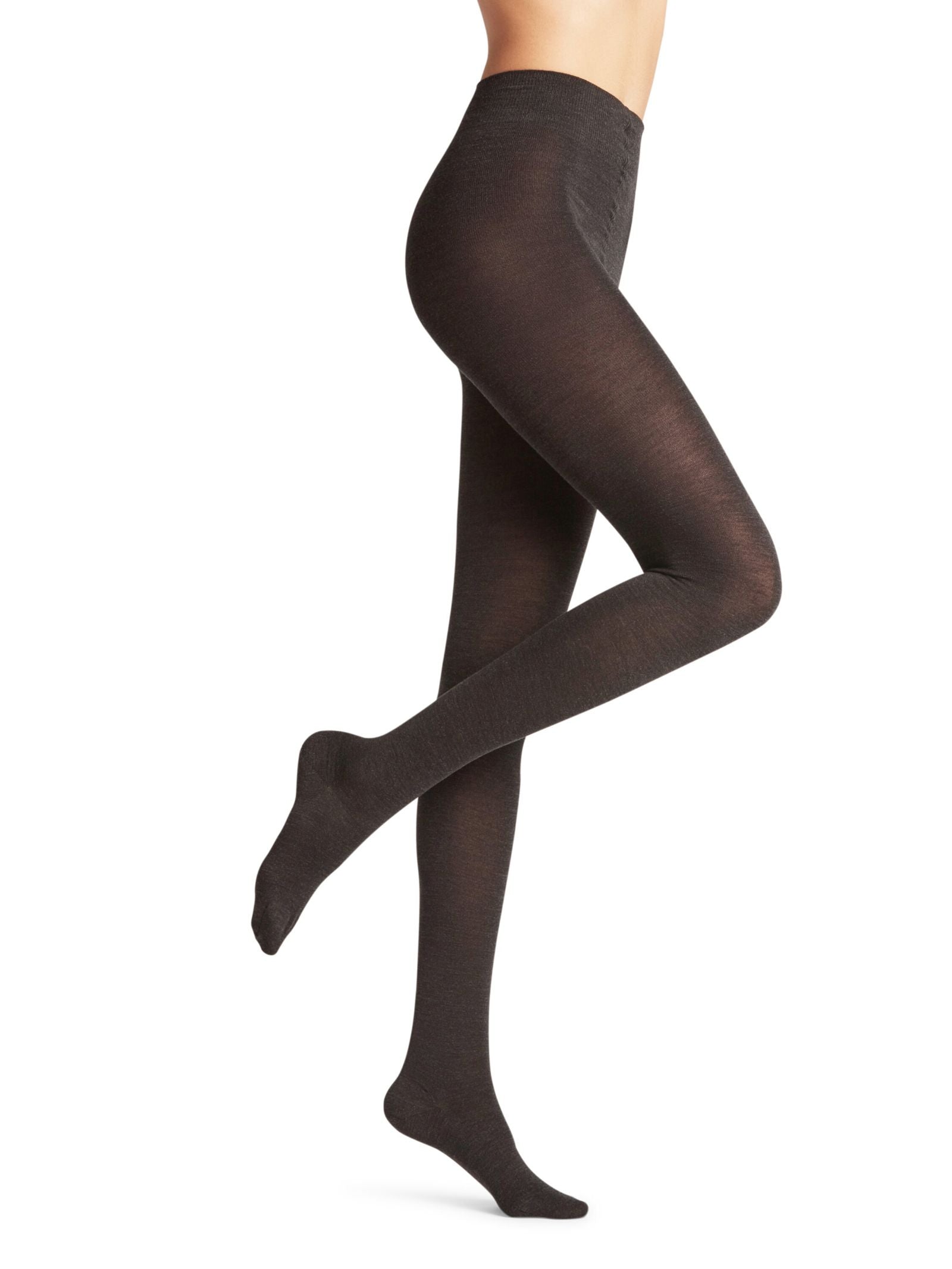 A person models FALKE Merino Tights in opaque black, standing on one leg with the other bent at the knee, shown from midriff to feet against a white background.