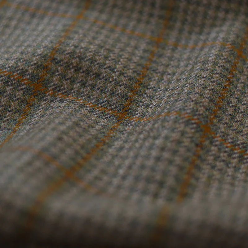 Close-up of Campbells of Beauly House Tweed 71958, showcasing its grey and brown houndstooth with orange windowpane lines. The soft, textured finish reflects the heritage craftsmanship of traditional Scottish tailoring.