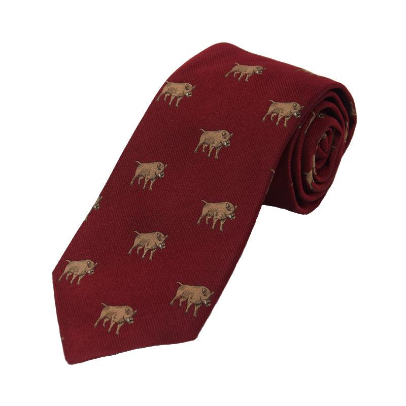 A rolled-up red Boar Silk Tie by Campbells of Beauly, handmade from silk and adorned with a repeating pattern of small, embroidered brown buffaloes—a charming countryside motif.