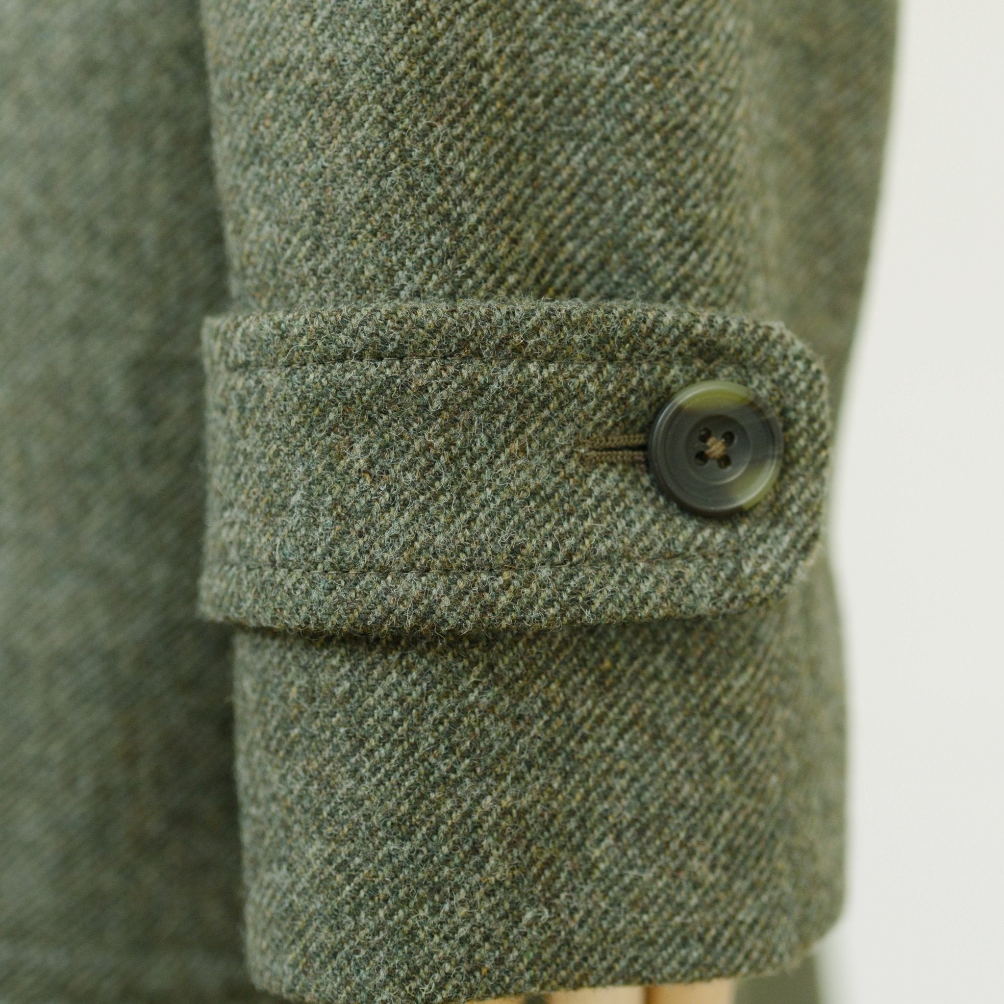 Close-up of the Campbells of Beauly Heath Collar Coat sleeve in greenish-grey wool, showcasing a refined black buttoned cuff—perfect for elevating everyday wear.