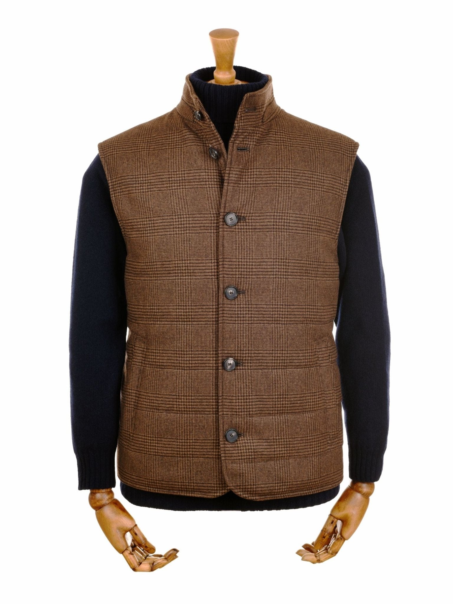 The Cashmere Gun Club Quilted Gilet by Campbell's of Beauly, featuring a brown plaid pattern and button closure, is styled over a black long-sleeve sweater on a wooden mannequin with visible hands, set against a white background.