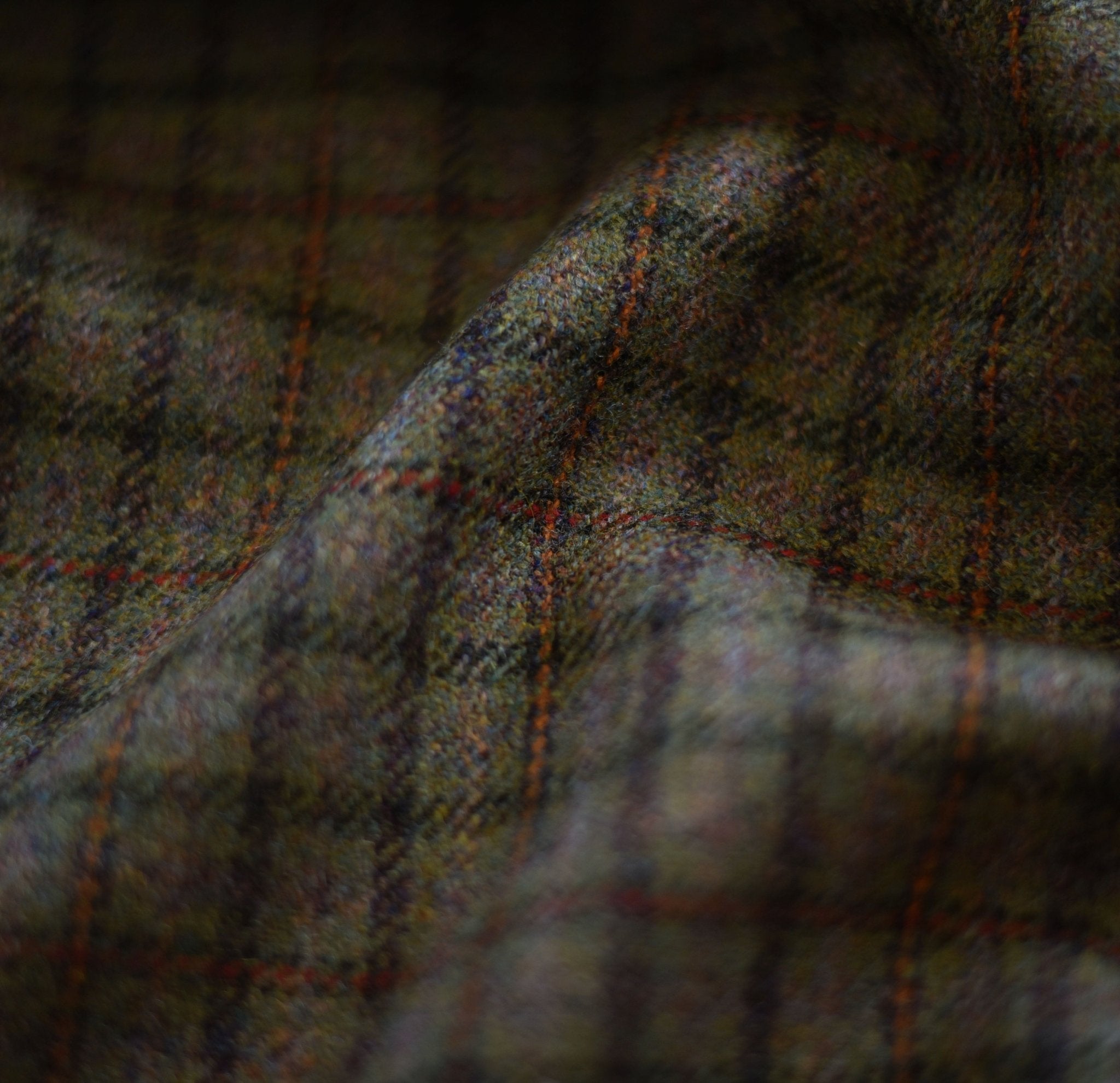 Close-up of Campbells of Beauly House Tweed 78704, featuring a subtle tartan in dark green, brown, and blue. Soft folds and shadows highlight the expertly crafted Saxony fabric’s heritage quality.