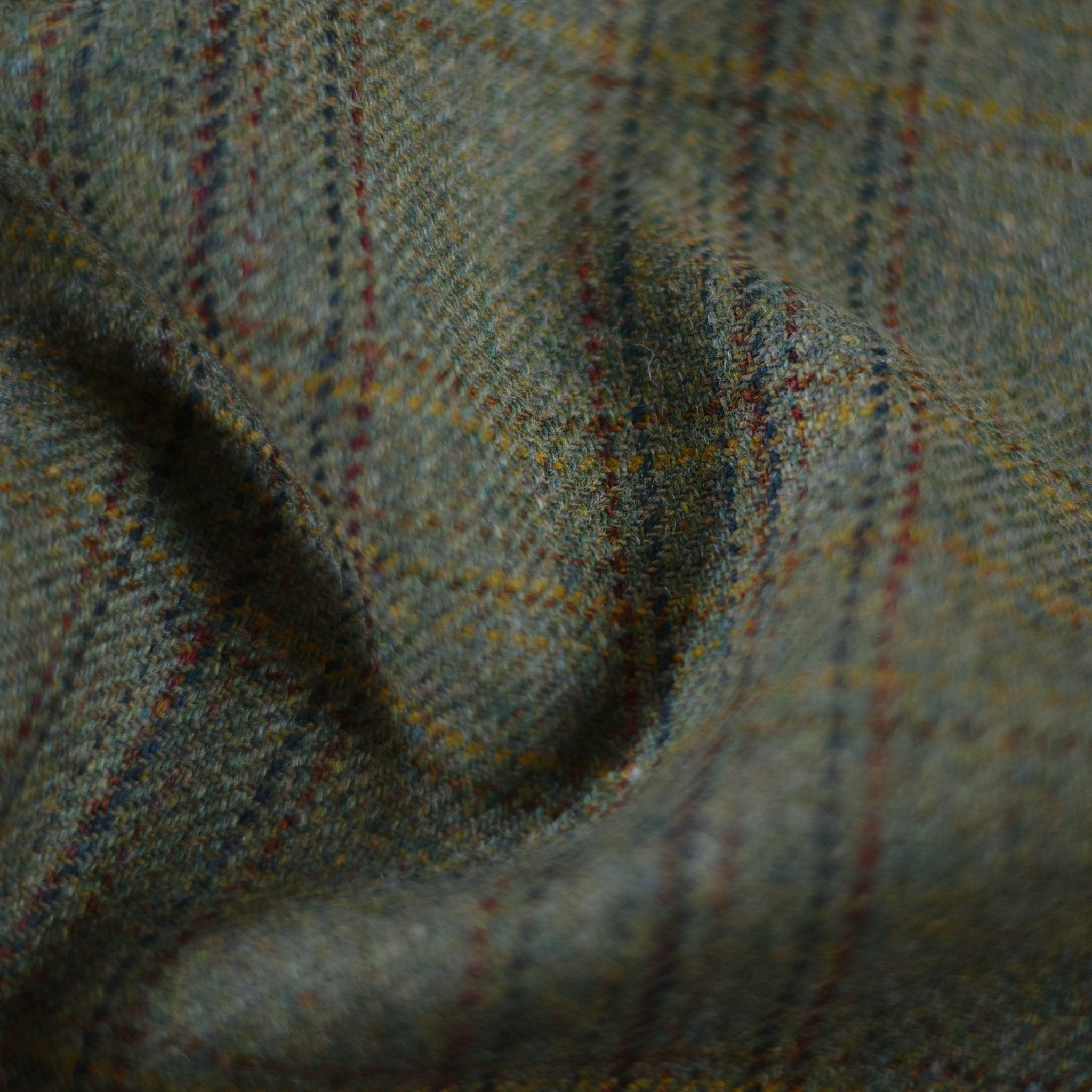 Close-up of House Tweed 57912 by Campbell's of Beauly, featuring green and brown plaid fabric that highlights its texture, weave, and fine Scottish craftsmanship.