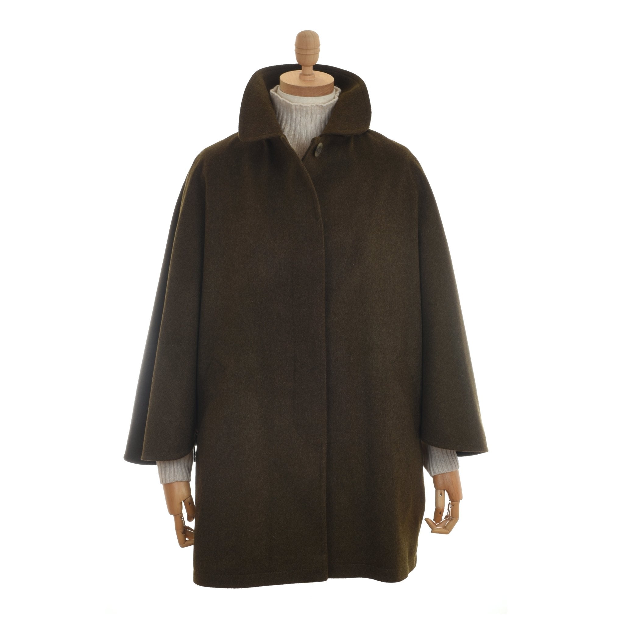 A mannequin displays the Campbells of Beauly Loden Green Cape with a high collar and wide sleeves, layered over a light ribbed turtleneck sweater, set against a plain white background.