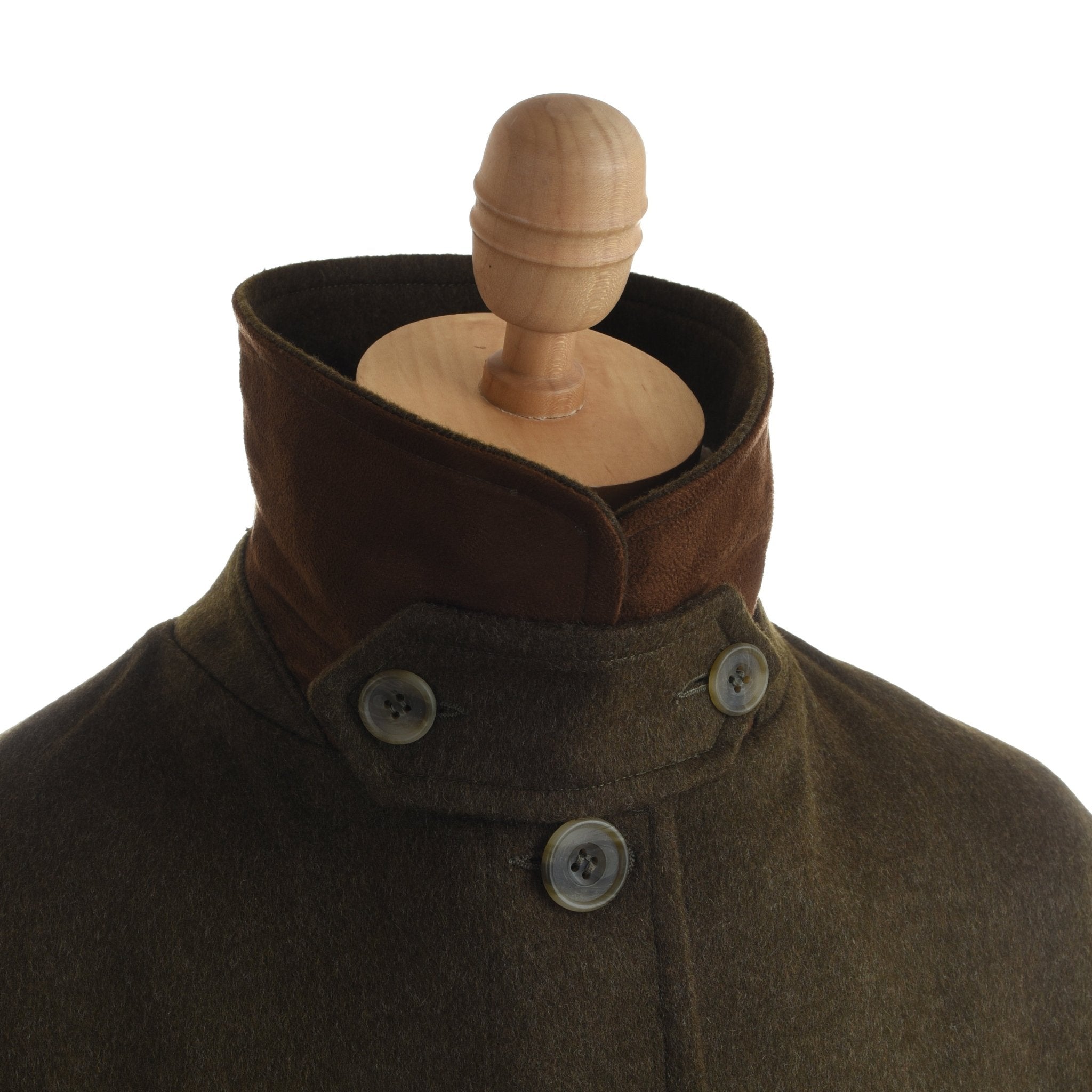 A close-up of the Loden Green Cape by Campbell's of Beauly, featuring heritage-inspired outerwear details and a high collar, displayed on a wooden mannequin against a white background.