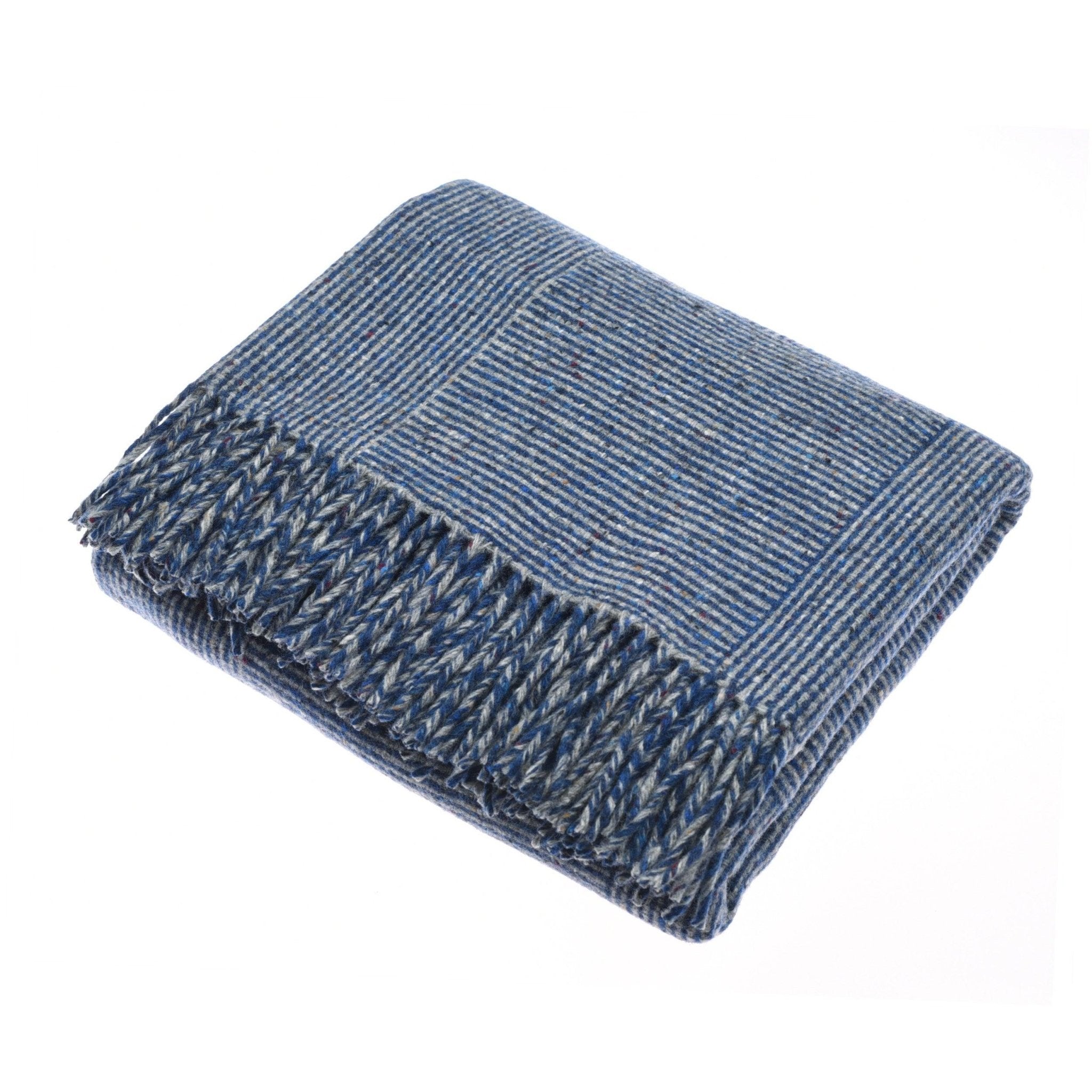 The Cabrich Lambswool Throw by Campbells of Beauly in indigo, featuring blue and white stripes and fringed edges, is neatly folded on a white background.