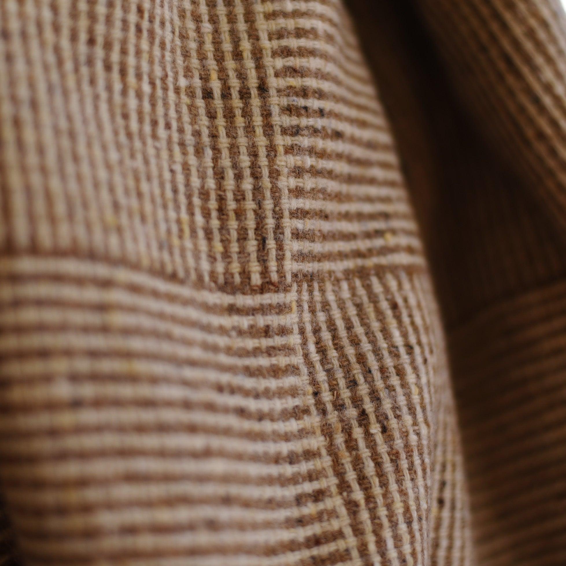 Close-up of the Cabrich Lambswool Throw by Campbells of Beauly, featuring soft brown and beige plaid with vertical and horizontal stripes in a textured, checkered pattern reminiscent of classic woolen blankets.