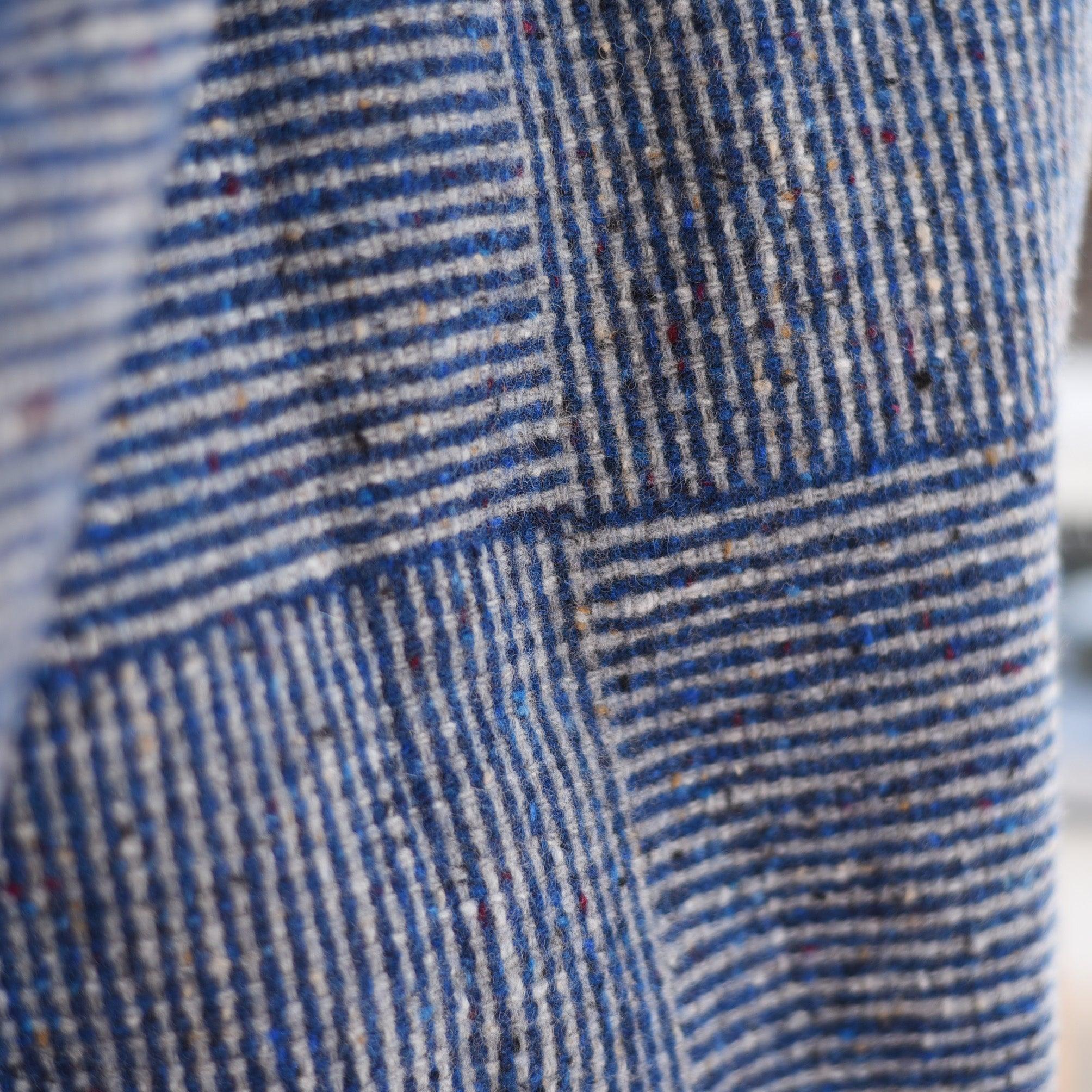 Close-up of the Cabrich Lambswool Throw by Campbells of Beauly, showcasing blue and beige woven stripes and grid patterns with colorful specks, evoking classic Donegal wool.