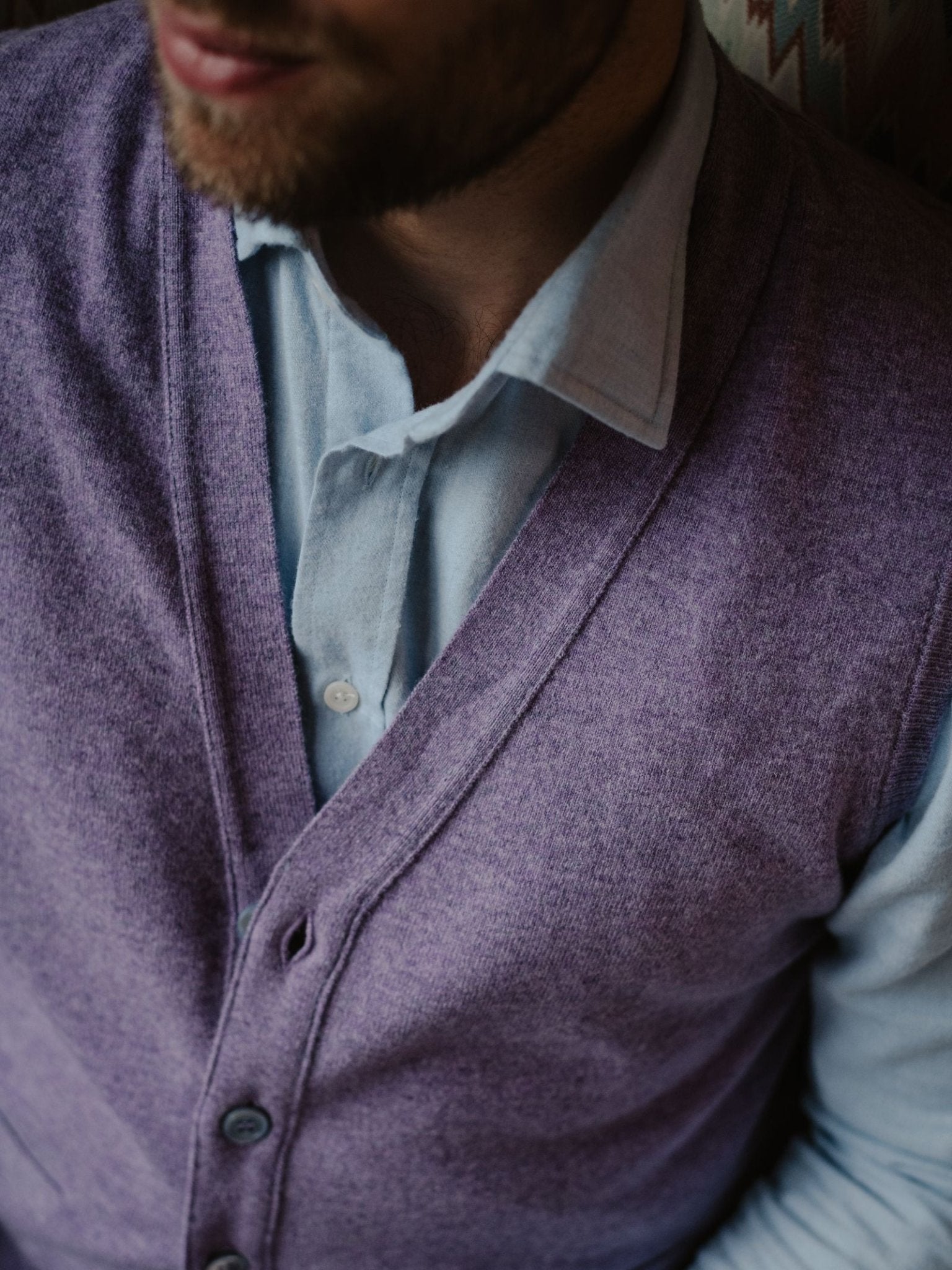 Close-up of a man in Campbell's of Beauly Auld Stock Geelong Button Waistcoat, crafted from soft Geelong merino wool in purple—a refined addition to any country wardrobe.