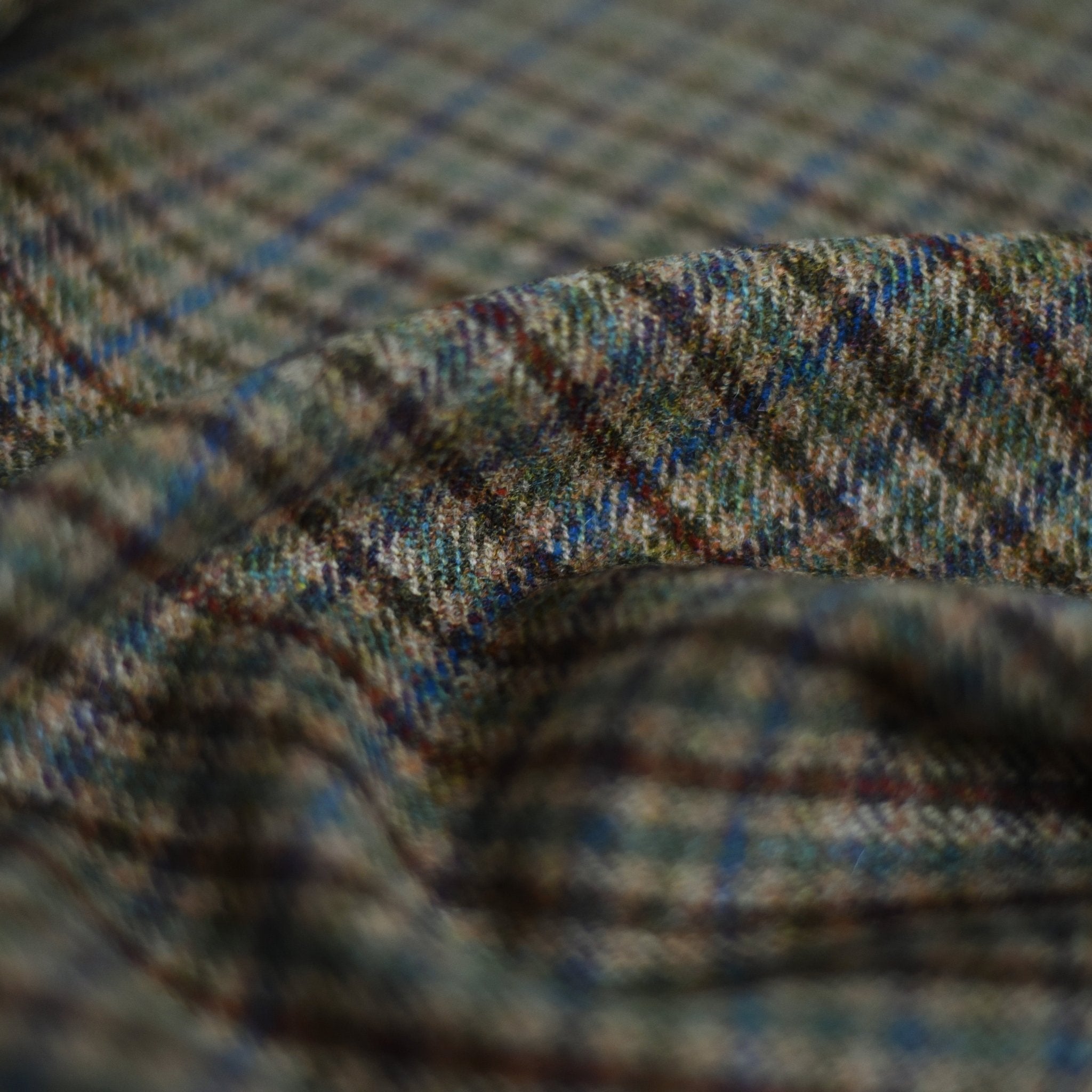 Close-up of Campbell's of Beauly House Tweed 84941, featuring textured, soft woven fibers and a plaid pattern in green, blue, brown, and gray tones reminiscent of classic Scottish tweed.