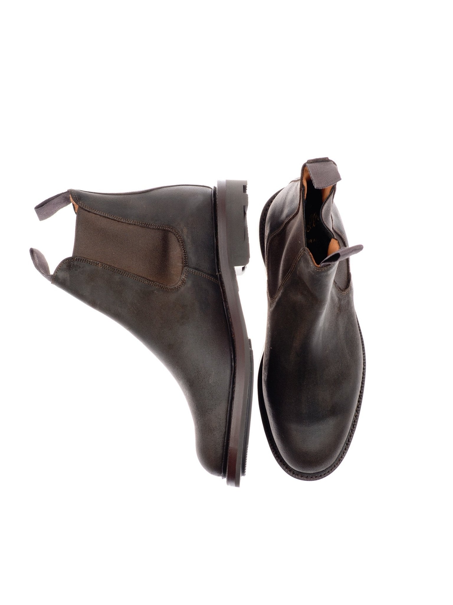 The Lowlander Boots by Campbell's of Beauly are dark brown leather Chelsea boots, handmade in England, featuring elastic side panels and pull tabs. One boot stands upright while the other lies on its side against a white background.