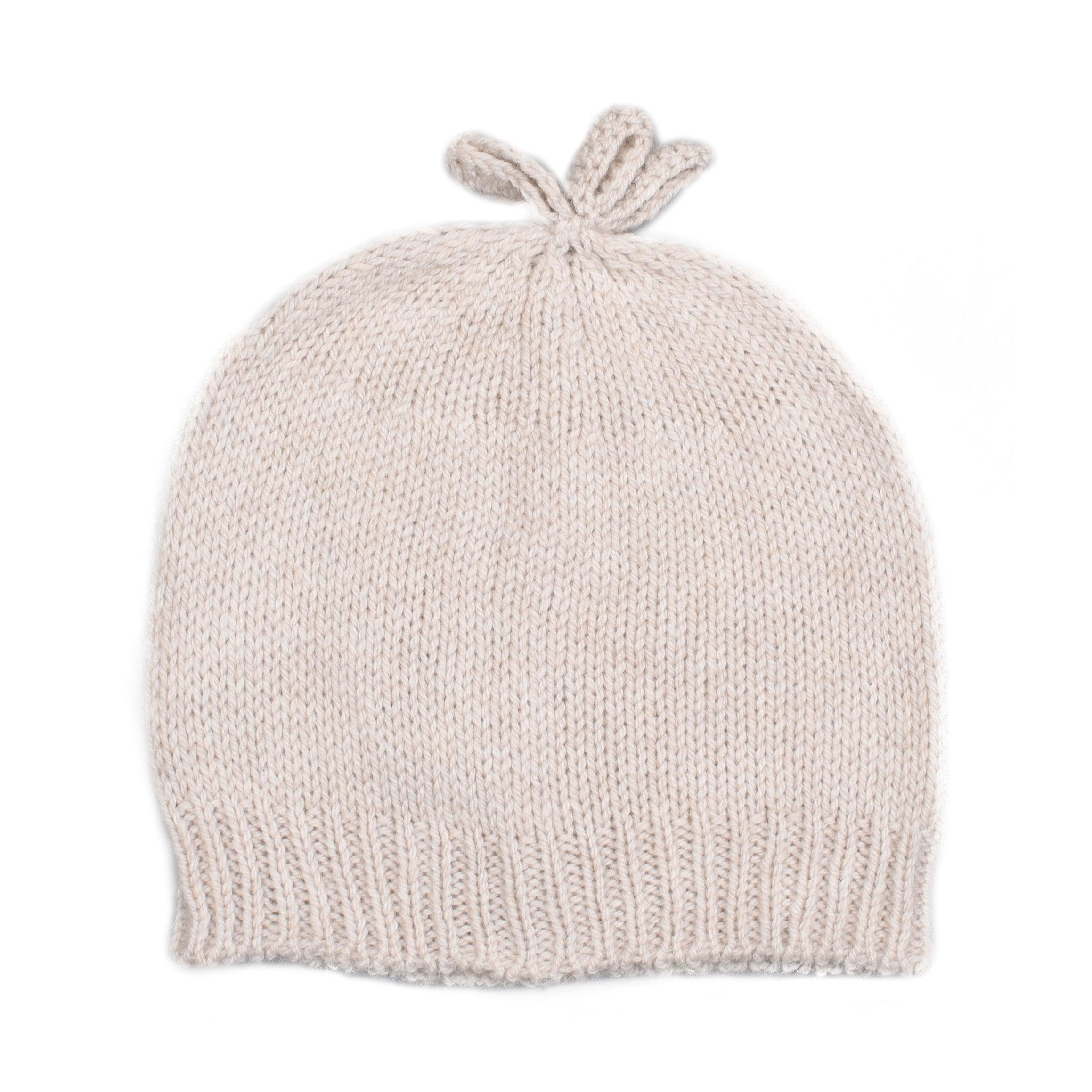 The Campbell's of Beauly Baby Lambswool Bonnet is a soft, hand-knitted beige hat with ribbed edges and two small loops on top, resembling bunny ears, shown on a white background.