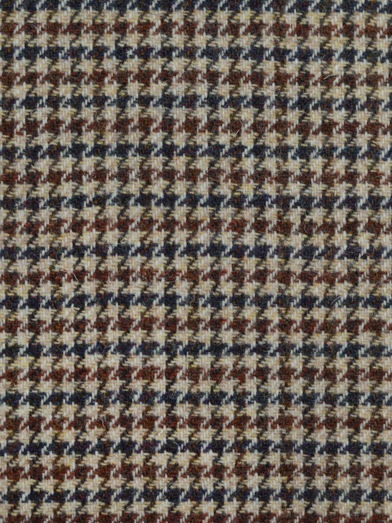A close-up of Harris Tweed 93896 by Campbell's of Beauly, featuring a brown, black, beige, and white houndstooth pattern made with traditional Scottish weaving techniques.