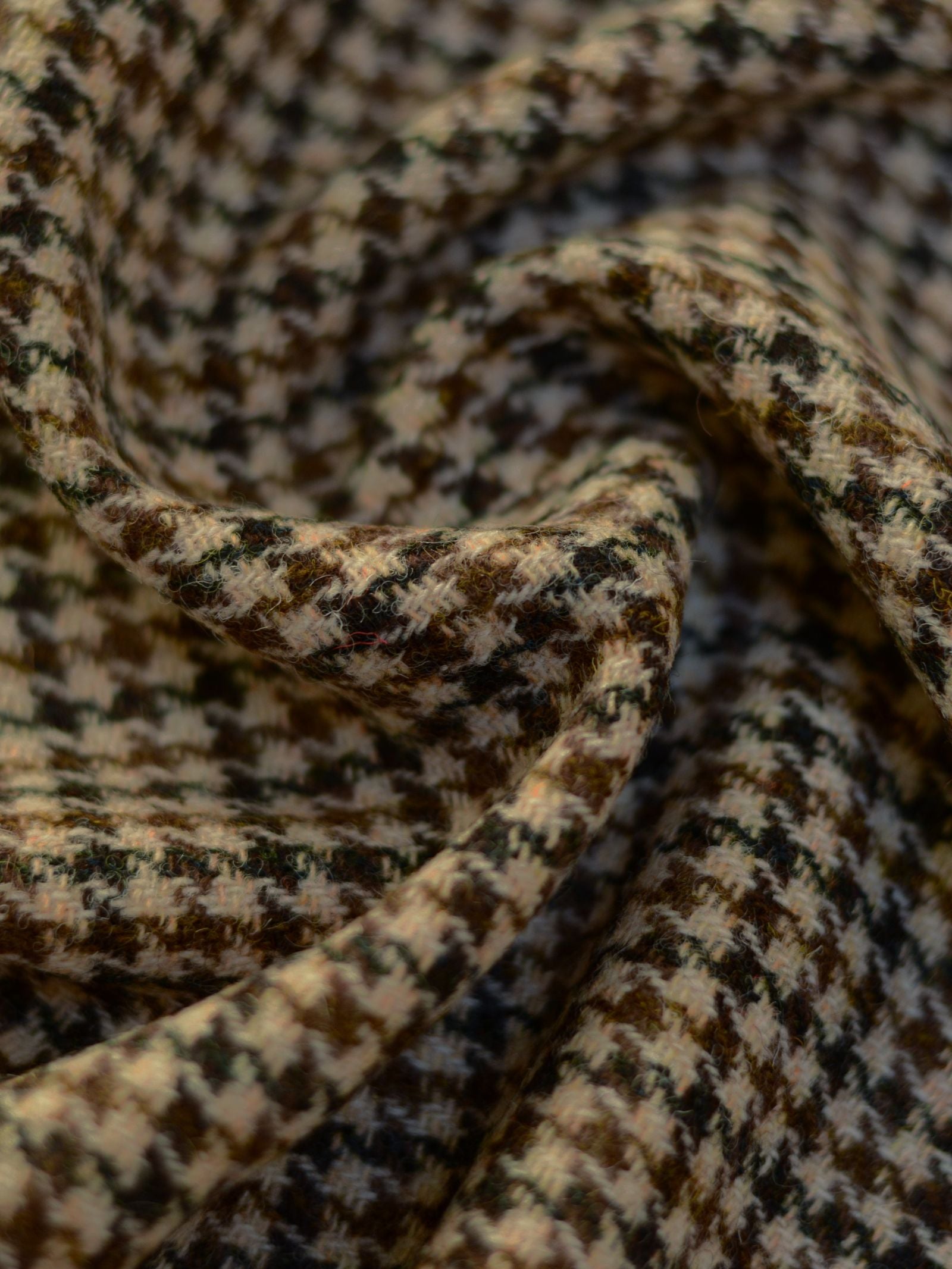 Close-up of Harris Tweed 93909 by Campbell's of Beauly—soft, featherweight tweed with brown, black, and cream houndstooth pattern, showcasing textured fibers and gentle draping inspired by classic Scottish tailoring.