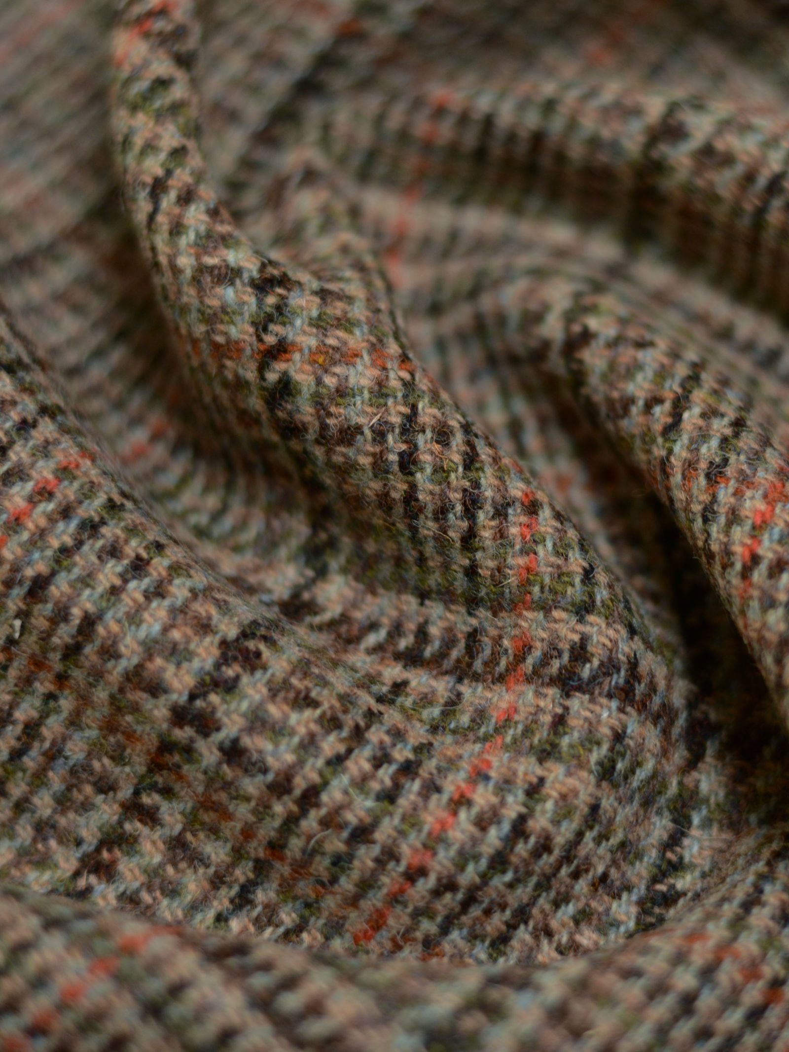 Close-up of Harris Tweed 93908 by Campbell's of Beauly, a brown and gray plaid fabric with orange and green stripes. The softly draped, slightly fuzzy texture makes it ideal for lightweight tailoring projects.