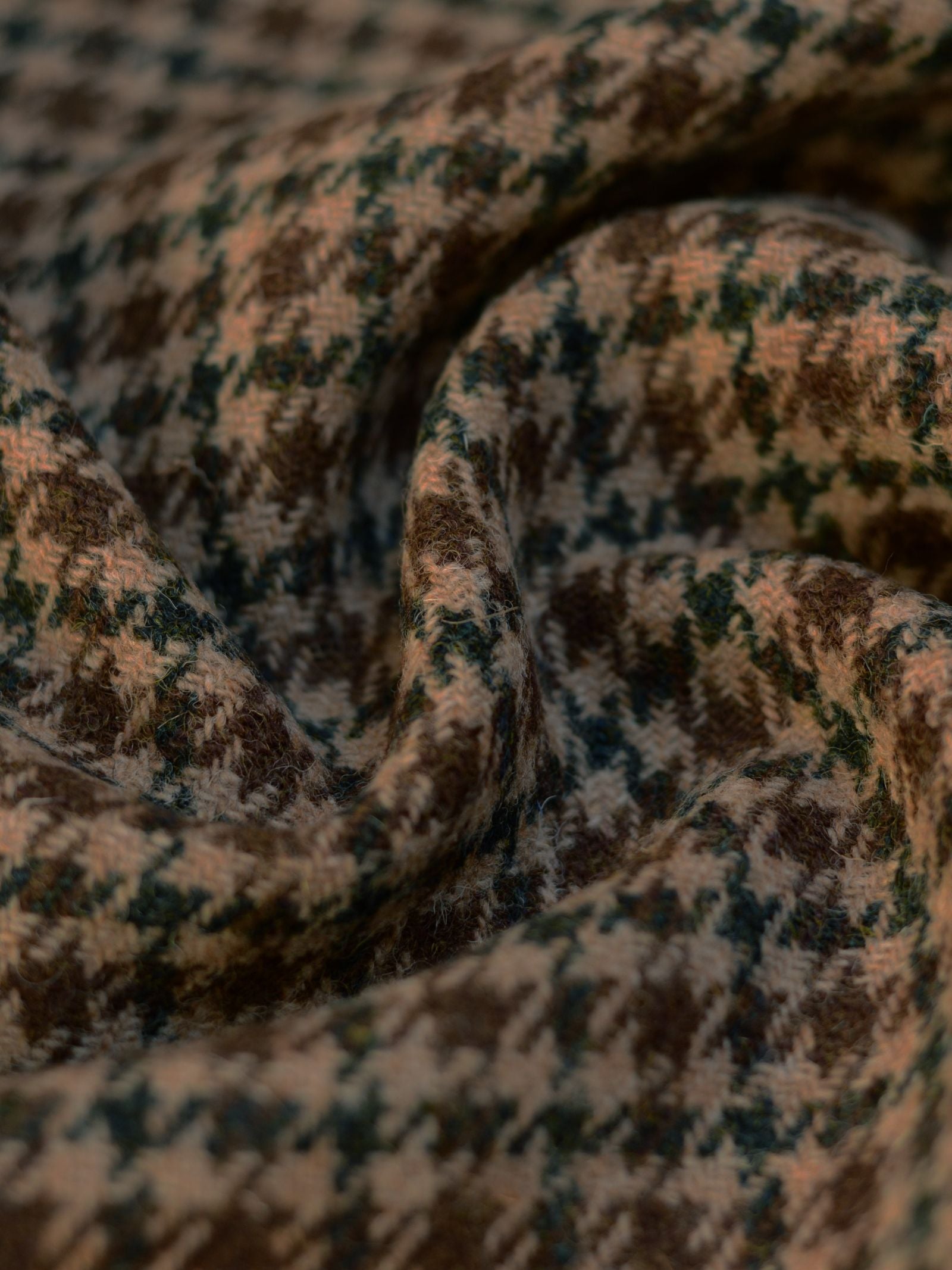 A close-up of Harris Tweed 93912 by Campbell's of Beauly shows its brown, beige, and dark green houndstooth pattern, soft textured surface, and detailed folds that highlight Scottish weaving craftsmanship.