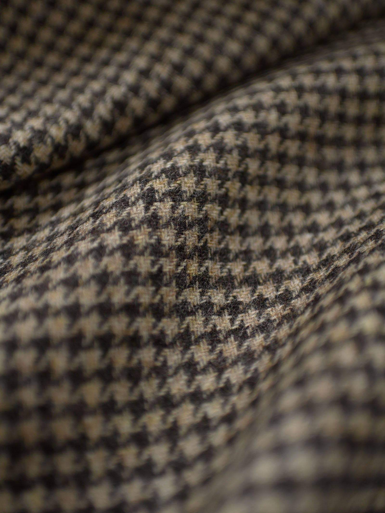 Close-up of House Tweed 83654 by Campbell's of Beauly, featuring a brown and black houndstooth pattern in classic Shetland Tweed jacketing weight, showcasing the weave and fabric folds.